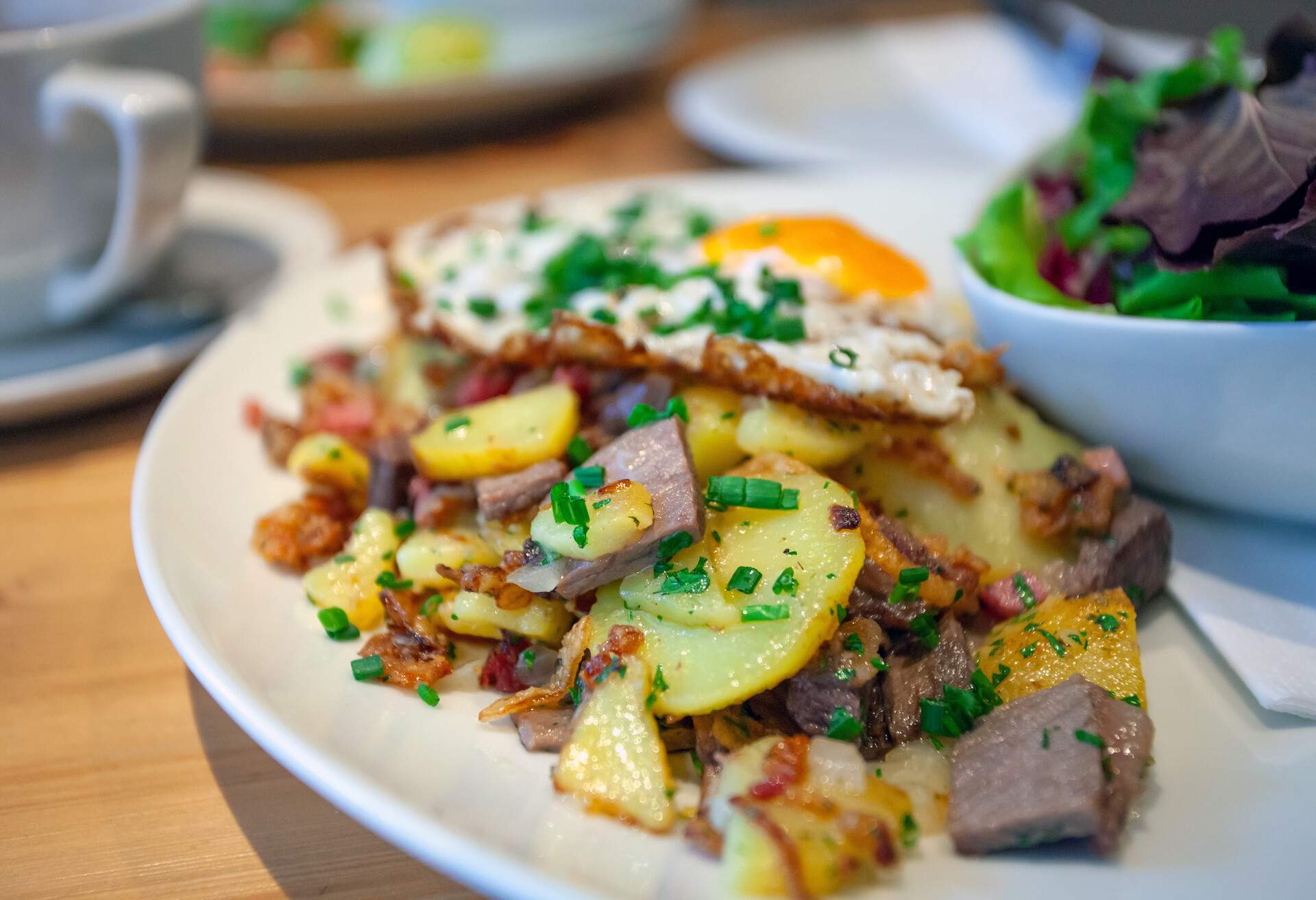 Tiroler Gröstl is a traditional dish from Tyrol you can find all around Austria. It is golden roasted potatoes with onion and ham. The dish is finished with chopped parsley and a fried egg.