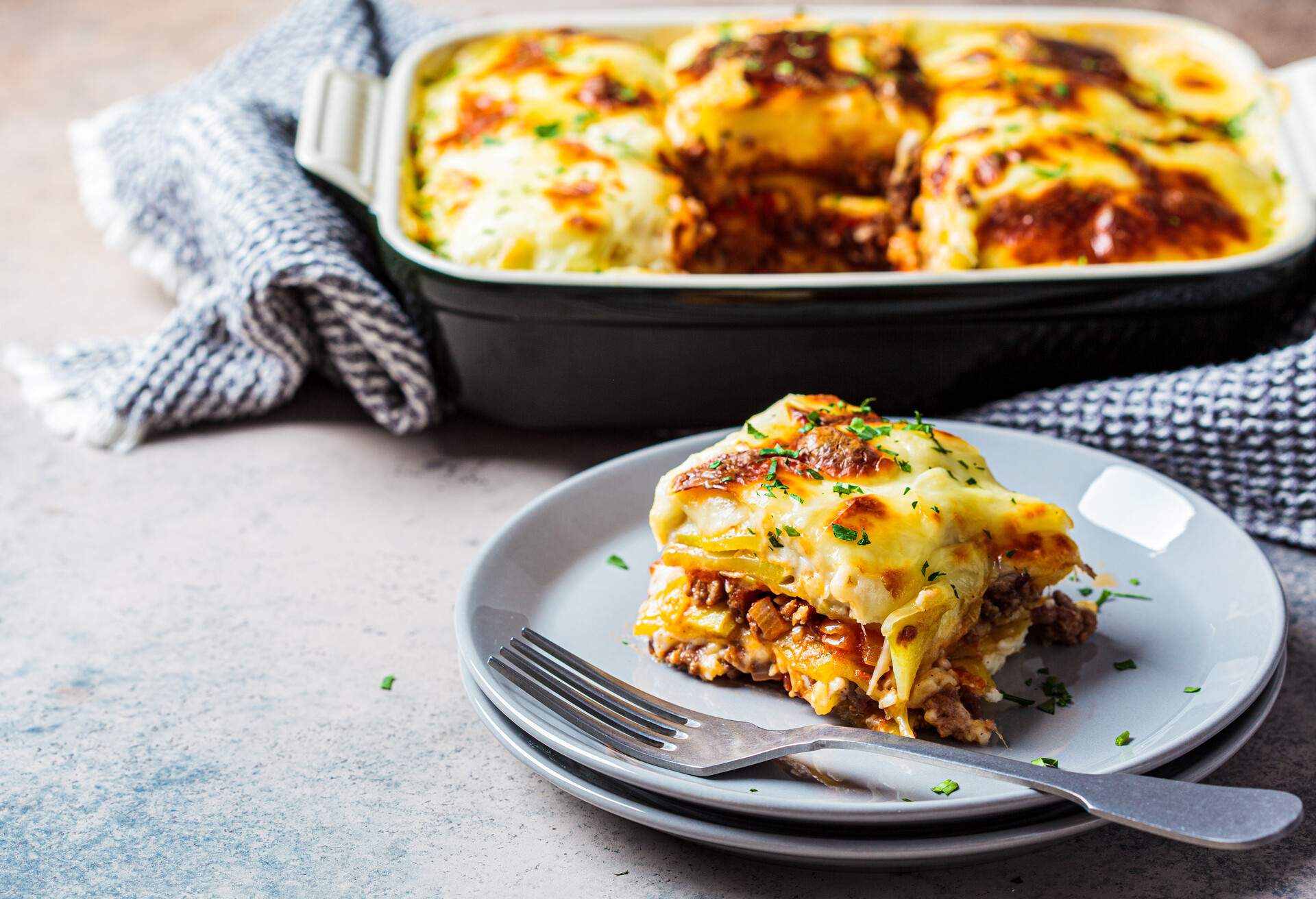 Traditional Greek potato and meat casserole with cheese - moussaka, dark background. Greek cuisine concept.