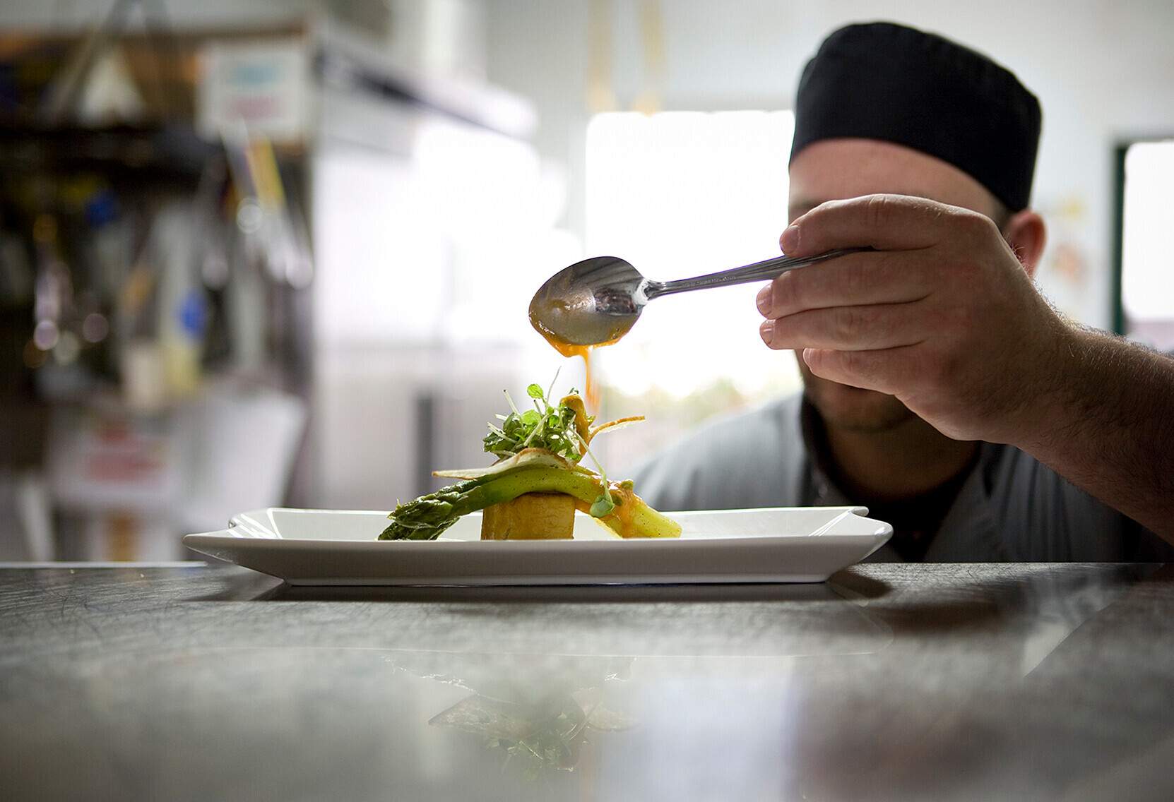 Chef's final touch. Seasoning asparagus on brioche with balsamic vinaigrette. Selective focus. Concepts; healthy eating; cooking; kitchen.