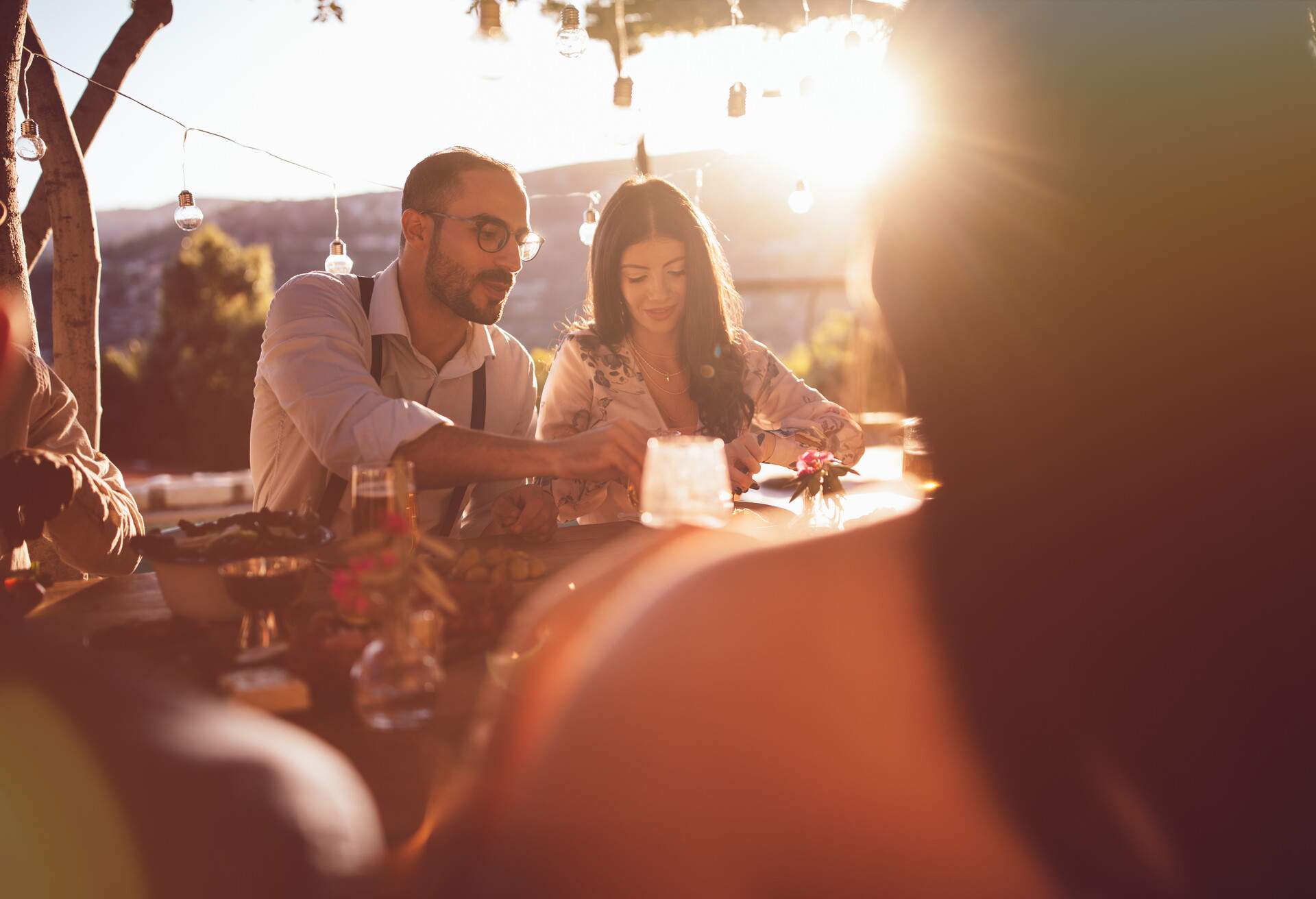 Young elegant friends having gourmet lunch with view at rustic mediterranean restaurant on mountains