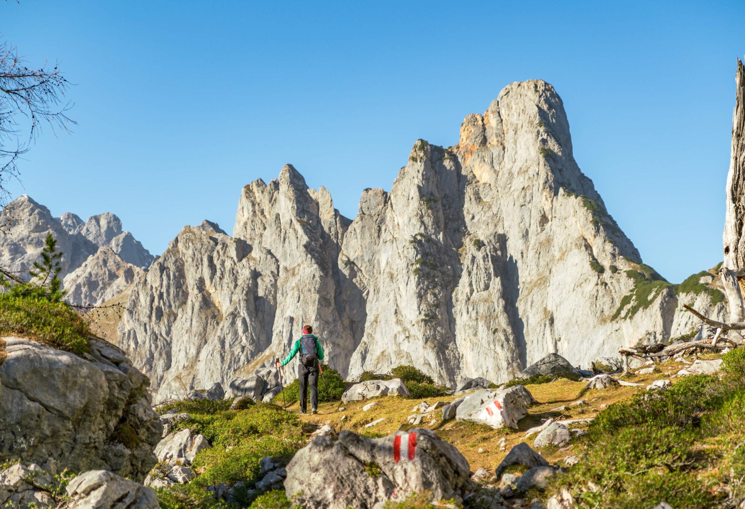 A hiker walking along the base of a limestone massif.