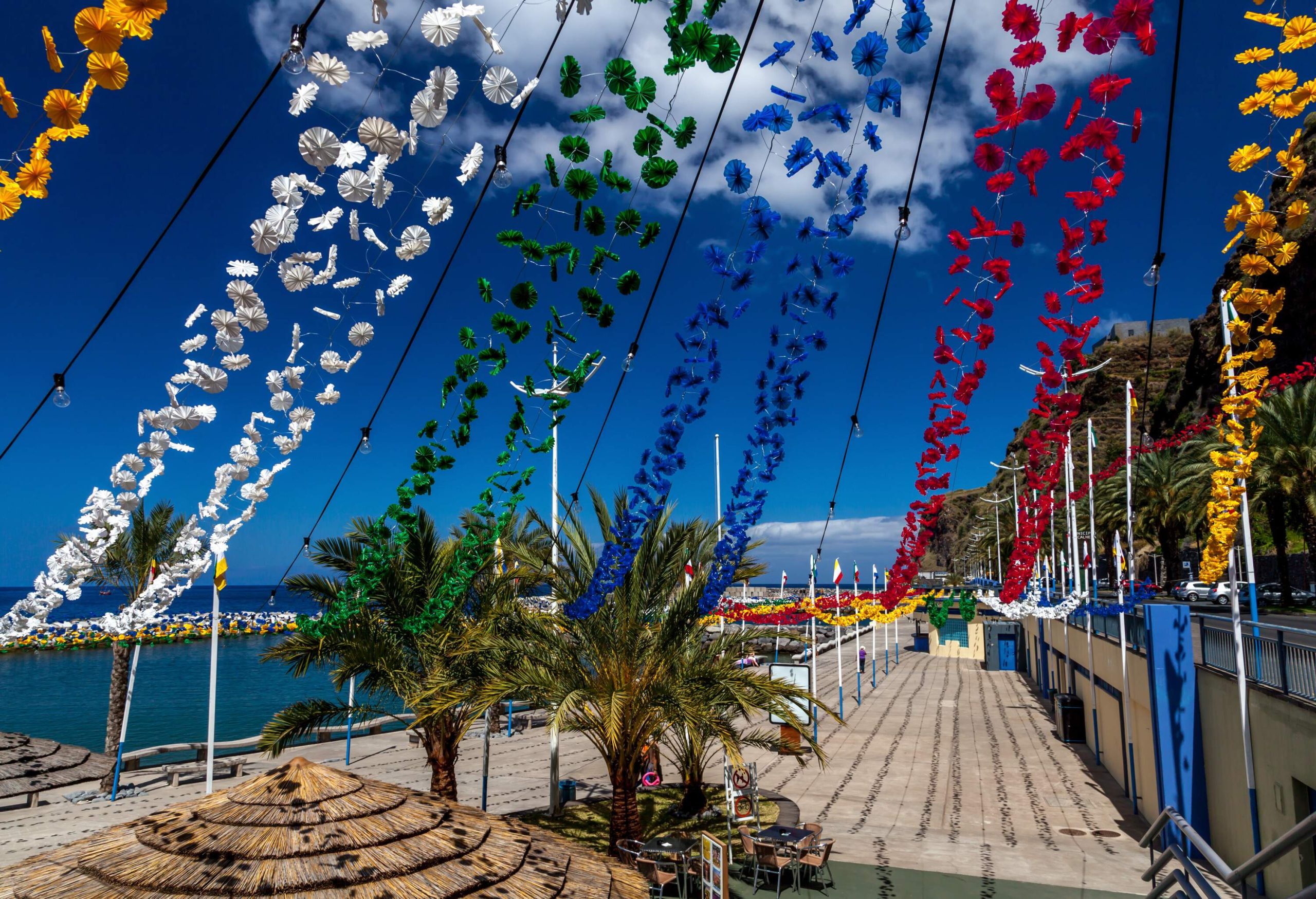 A seaside street adorned with paper flower garlands.