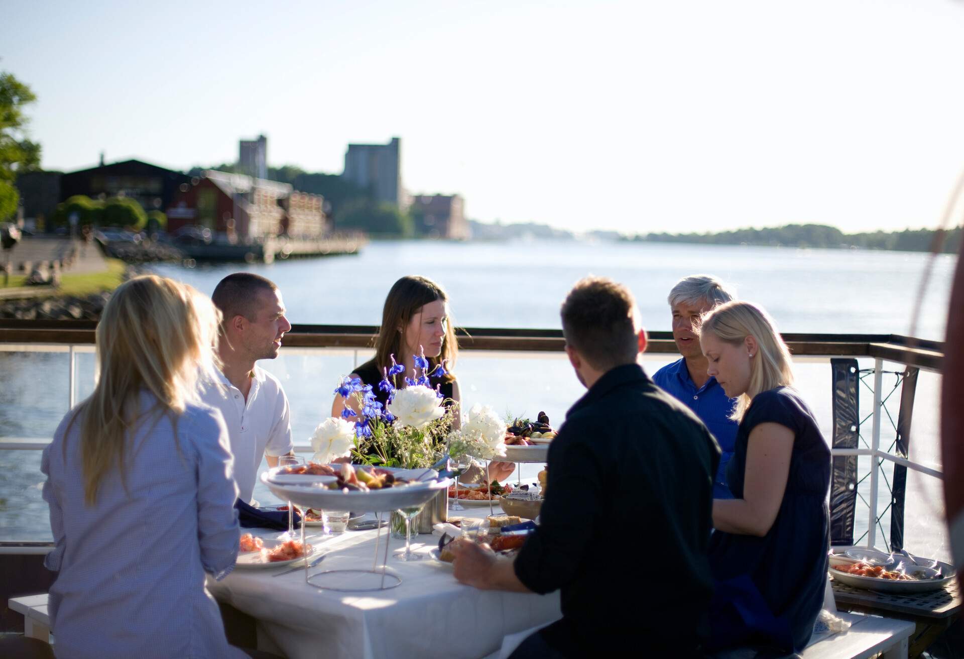 Group of friends dining al fresco on a balcony with a view of the lake.