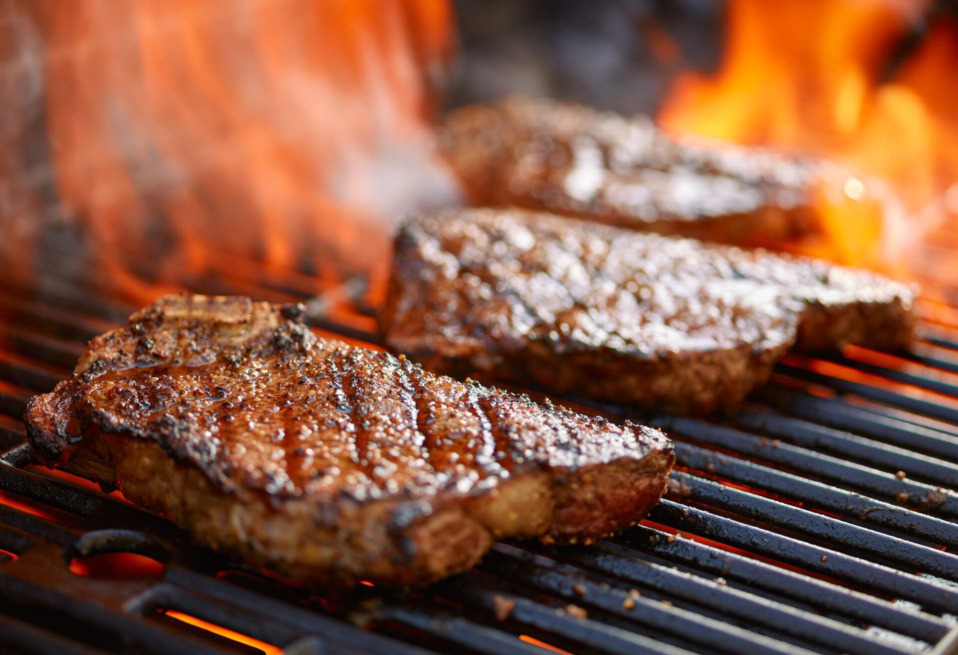 grilling steaks on flaming grill and shot with selective focus 