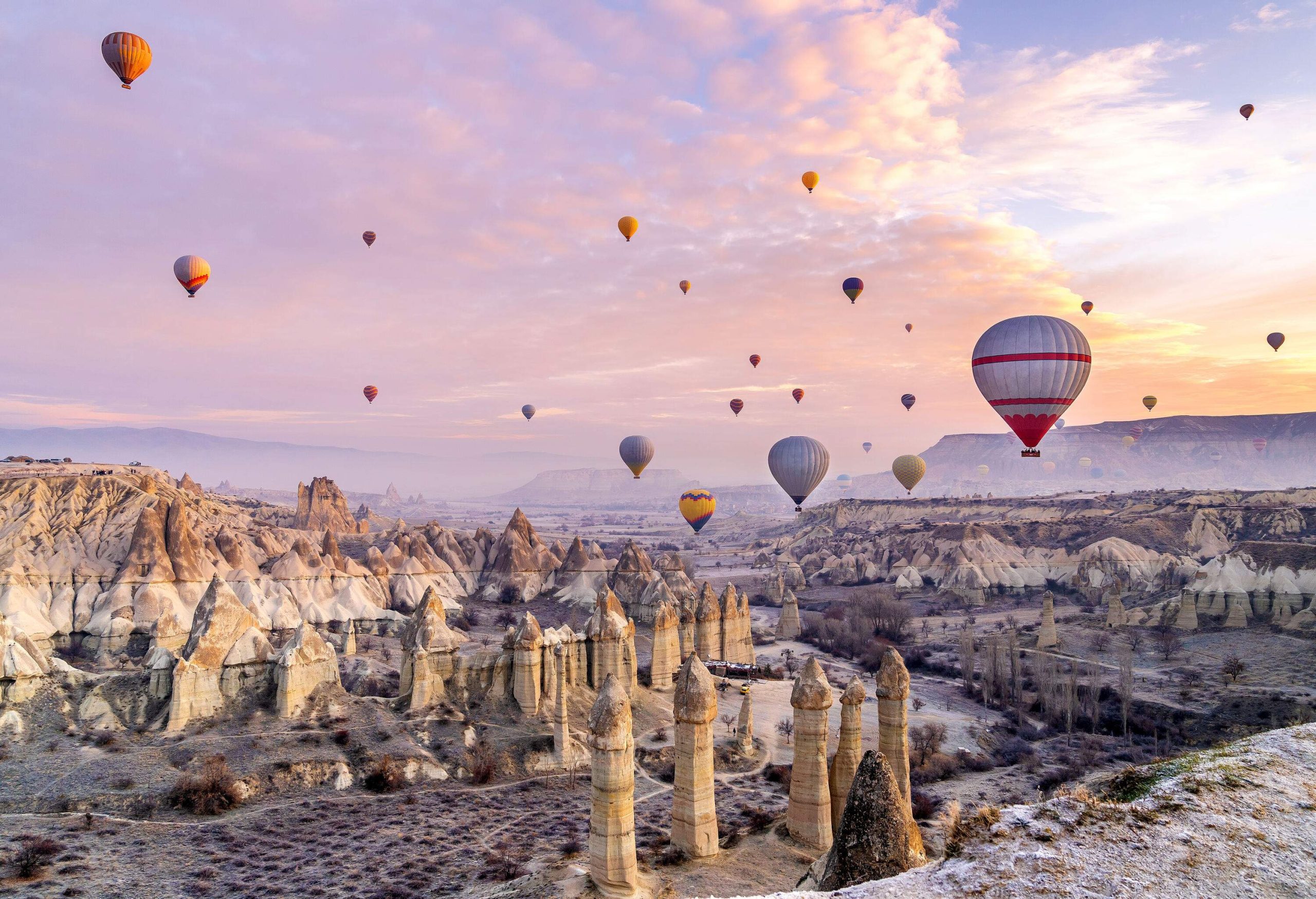 Colourful hot air balloons fly above the amazing rock formations landscaped in the valley.