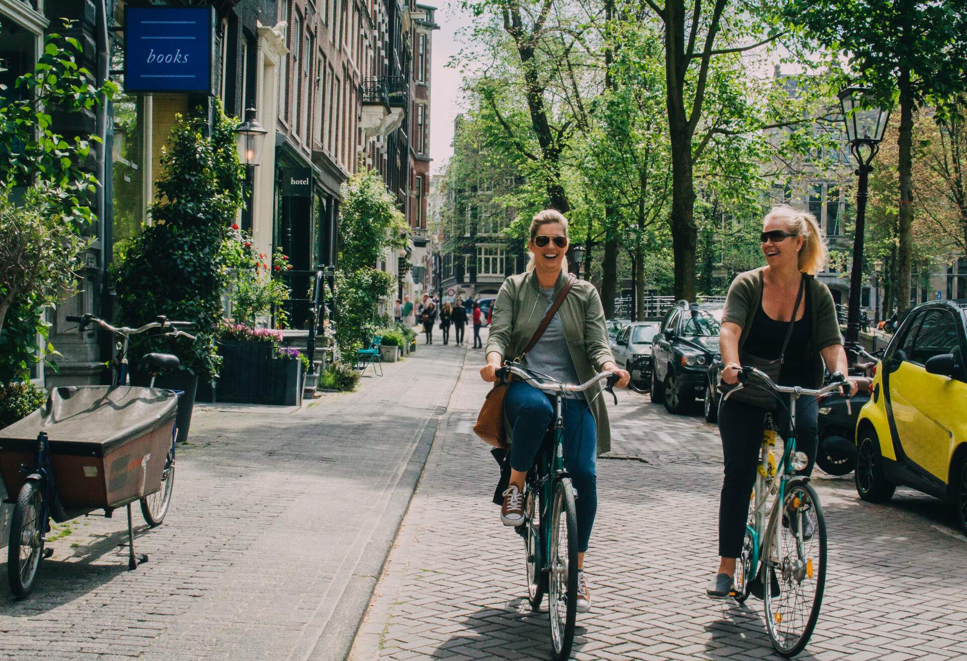 Two women riding their bikes in summer in Amsterdam, Netherlands