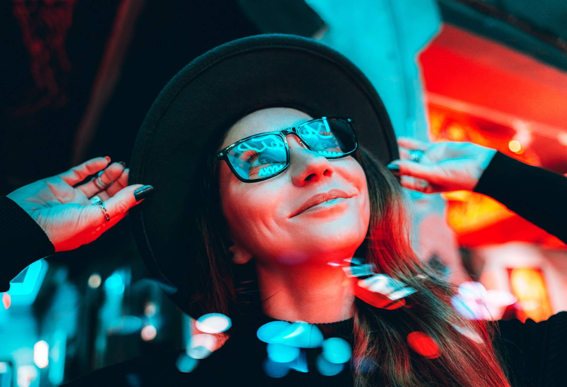 A woman wearing a black hat and glasses reflected the LED lights in front of her.