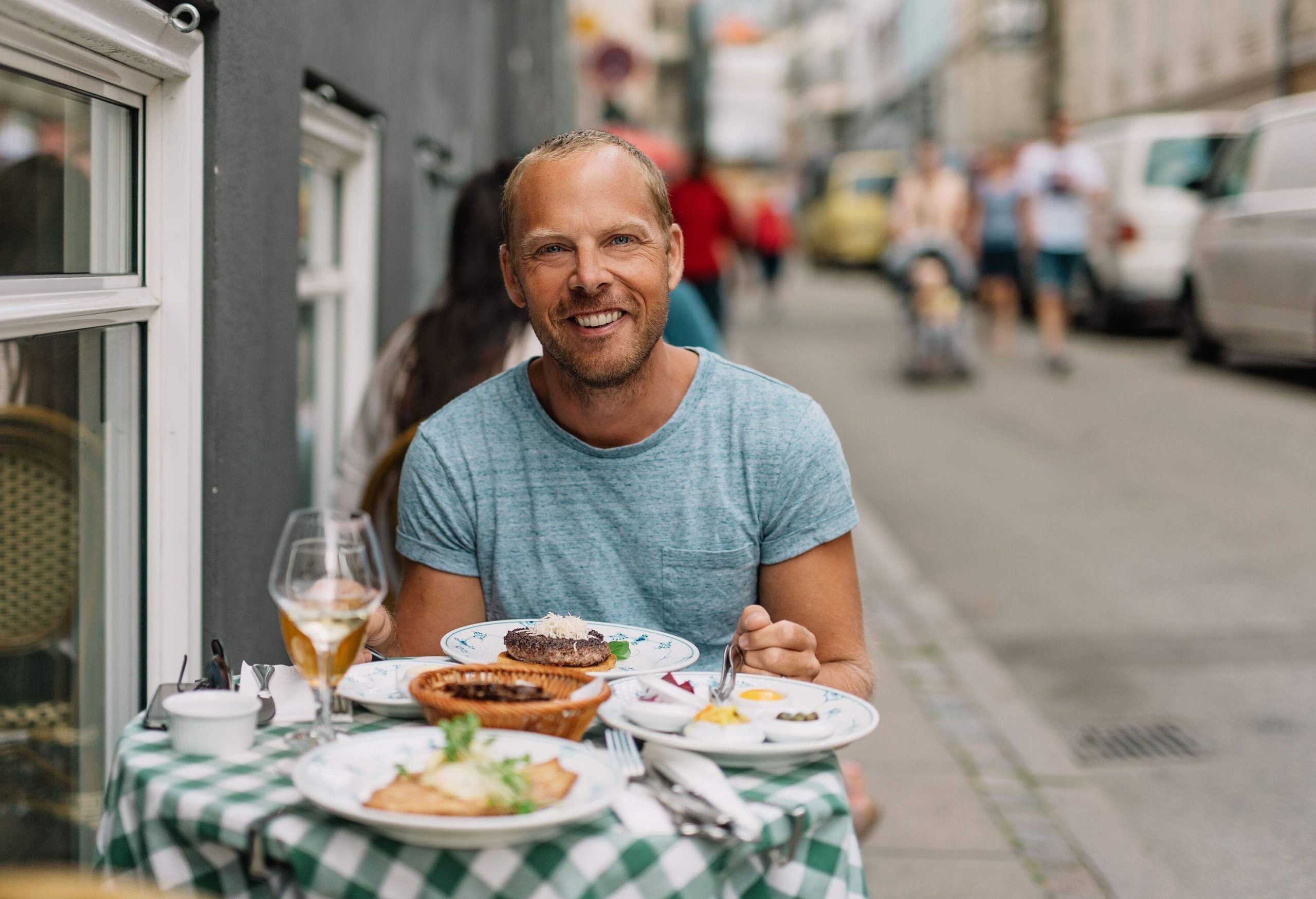 A man smiles as he sits in front of a table filled with food.