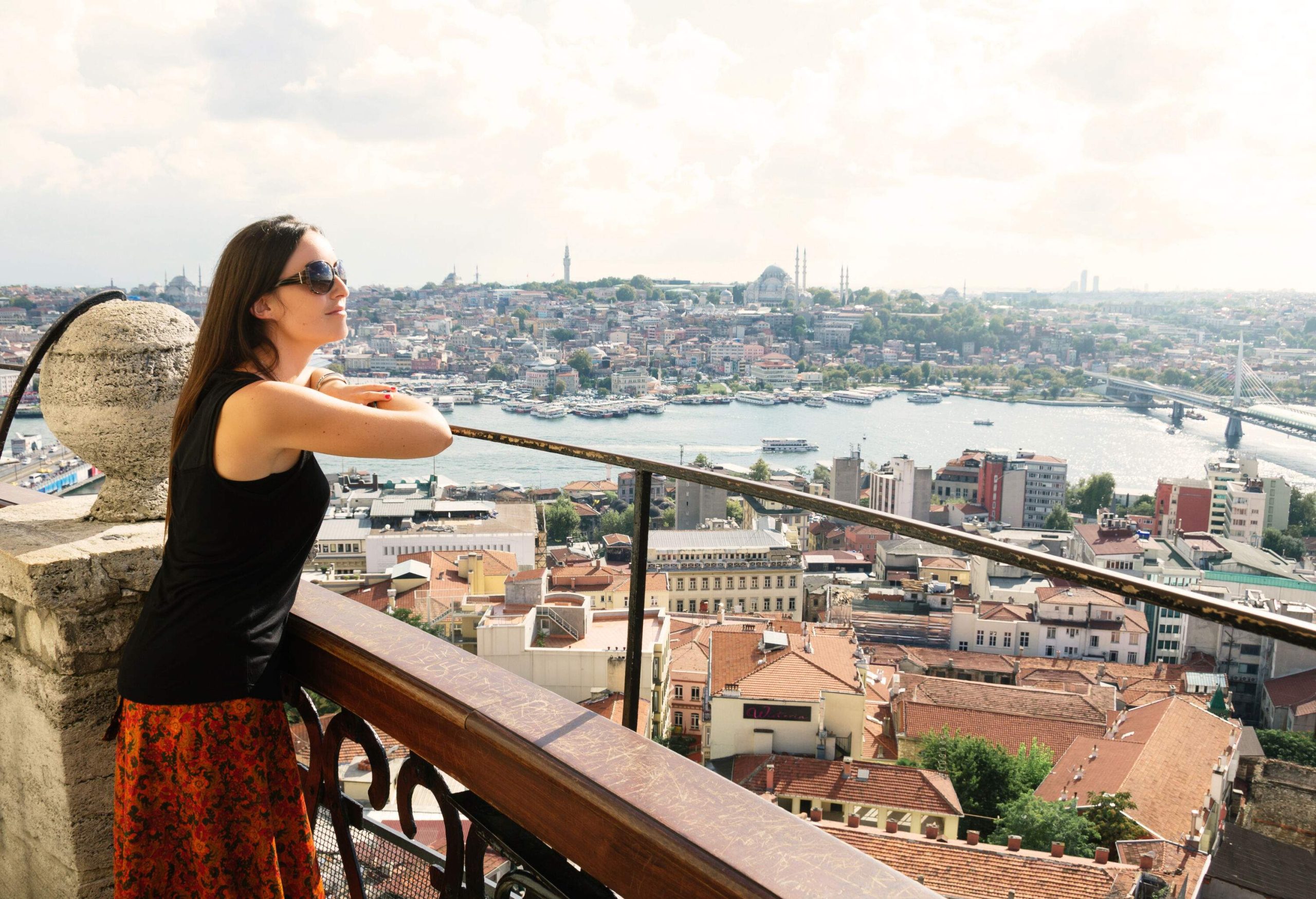 A woman leans out from a tower, taking in the breathtaking view of a city with an inlet running through its centre.