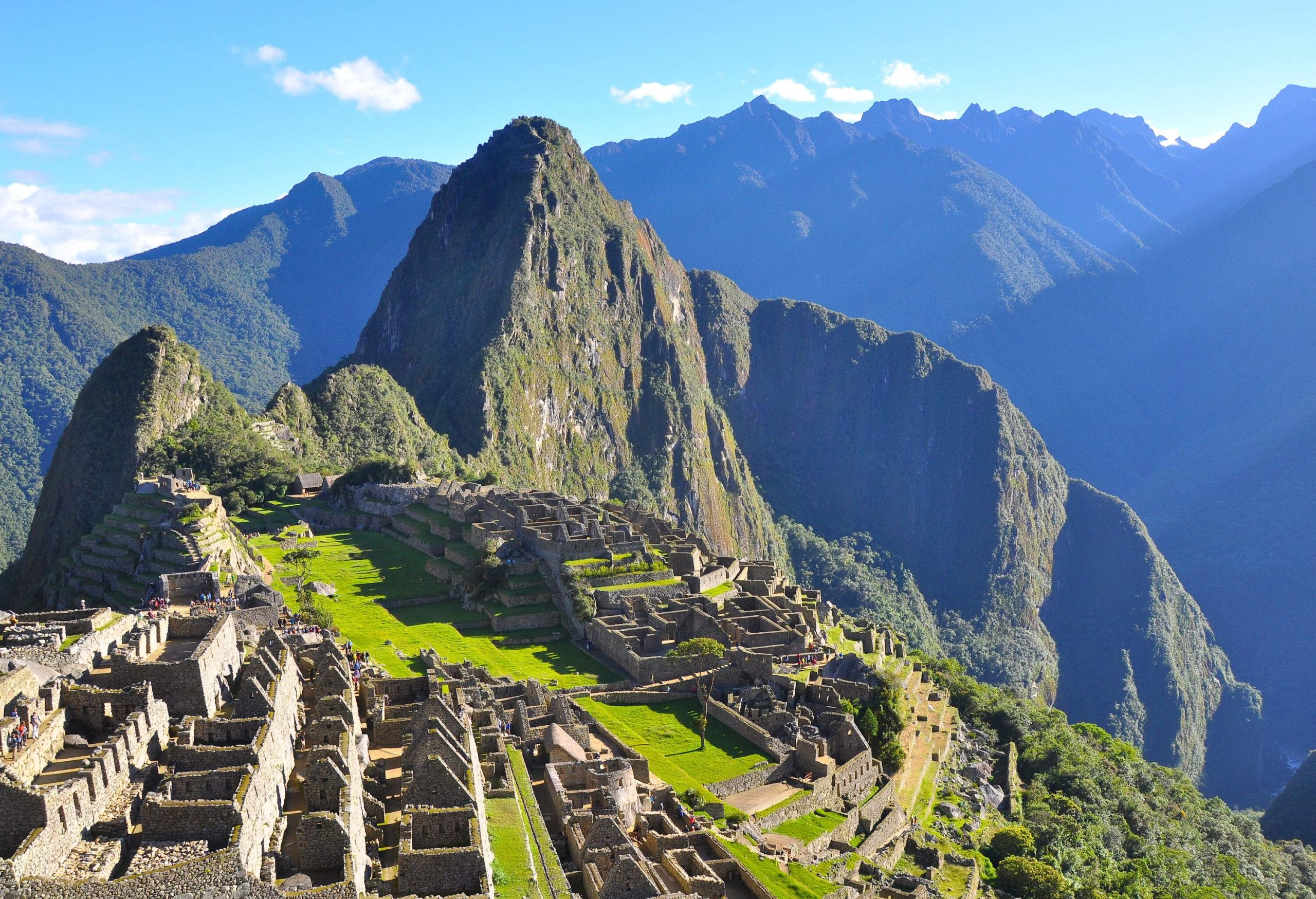 Terraced ruins of Machu Picchu, an ancient hilltop city beside mountains with rugged peaks.