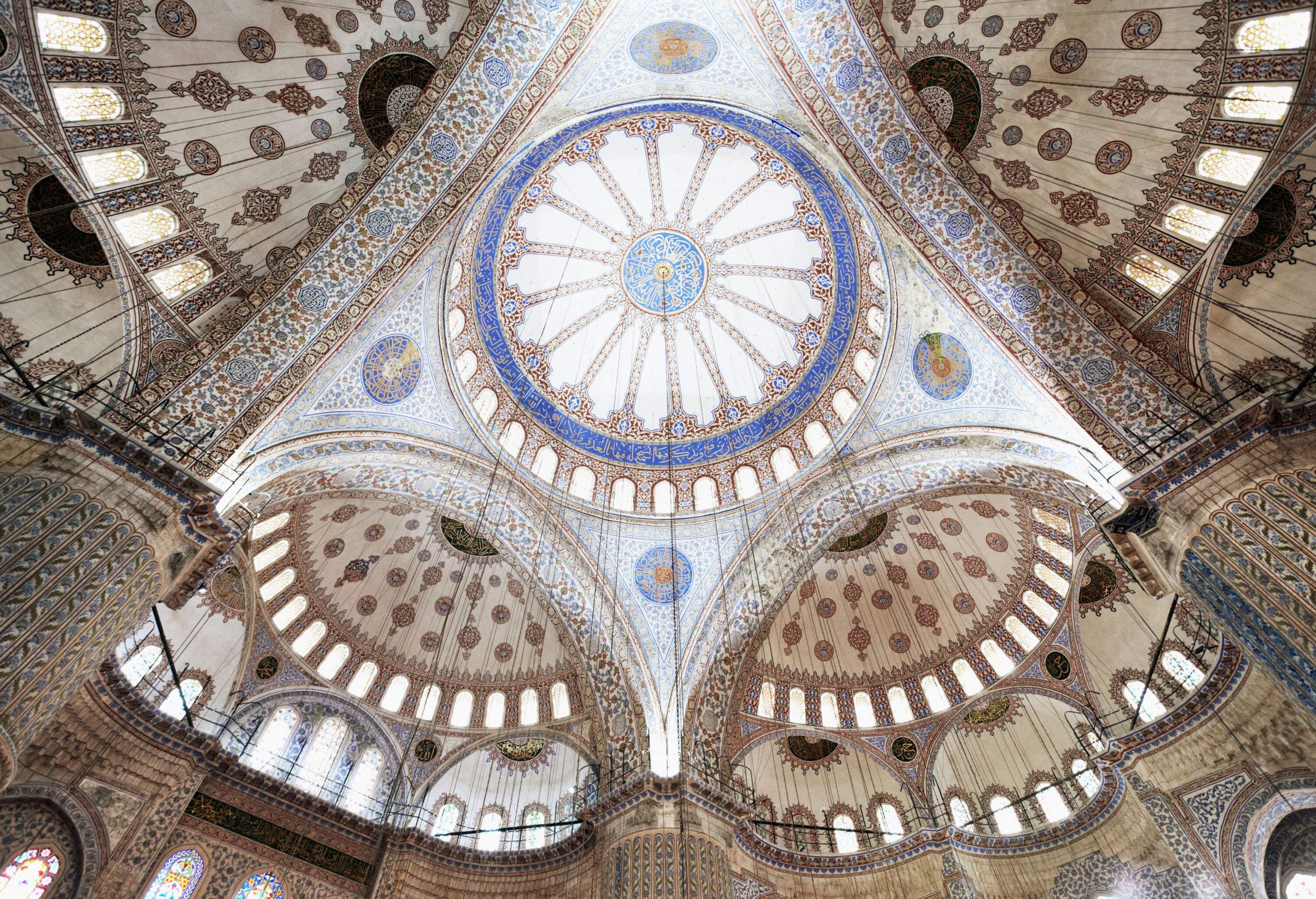 Lavishly decorated dome ceilings surrounded by stained glass windows.