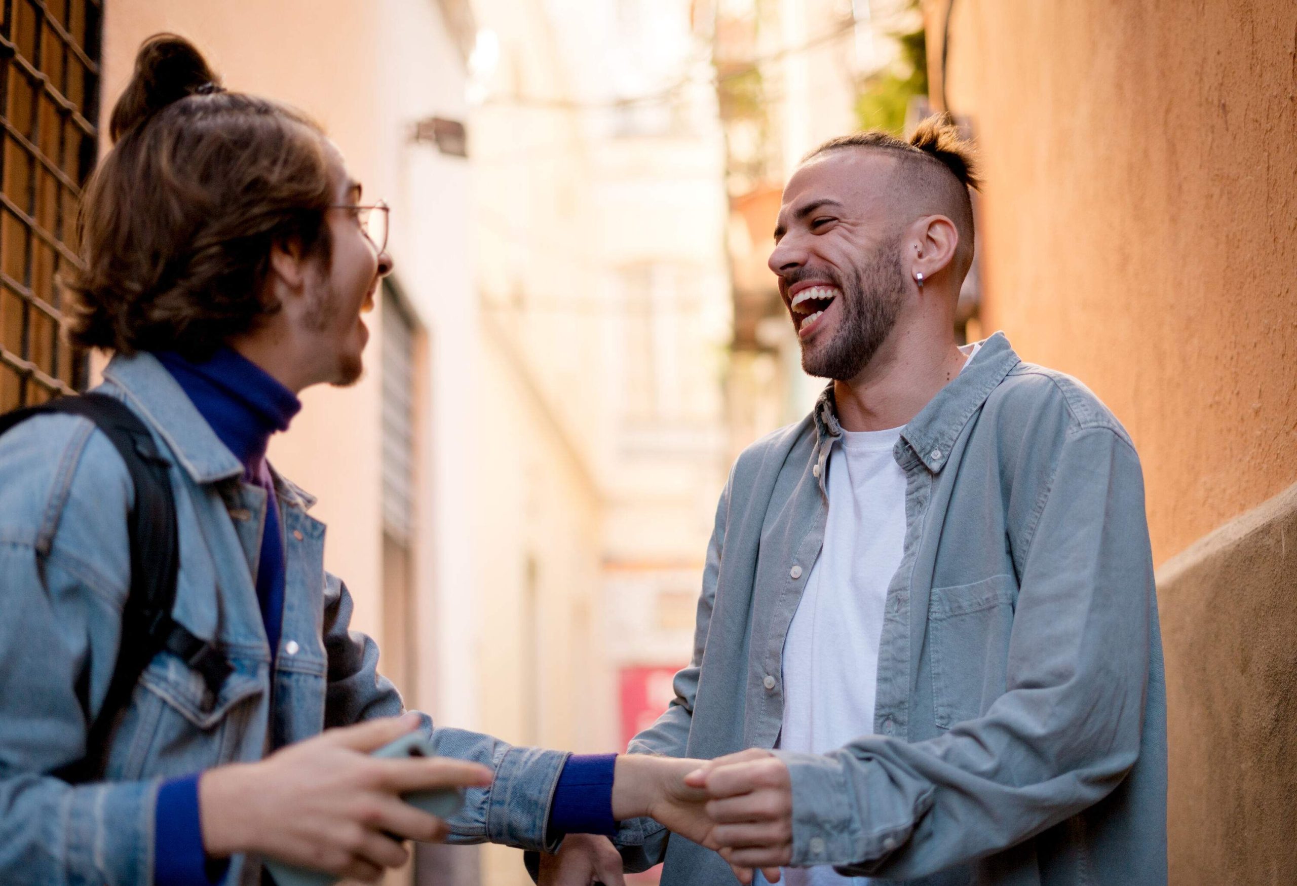 Two casually dressed men are laughing at each other.