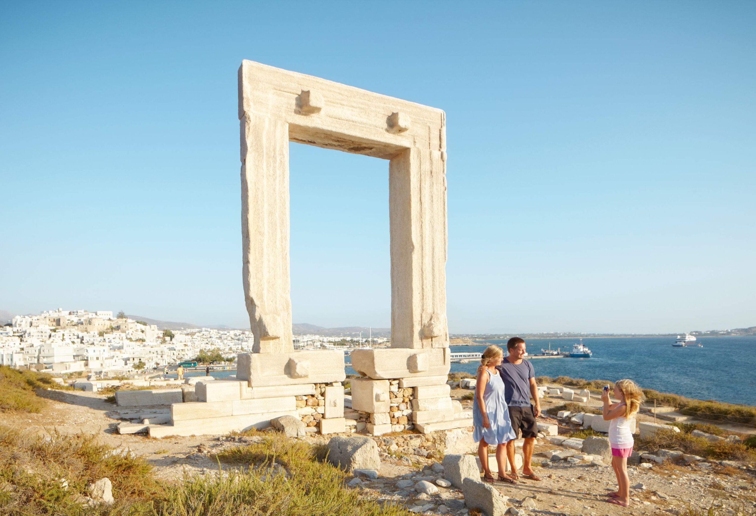 A woman taking a picture of a couple with a massive marble doorway behind them.