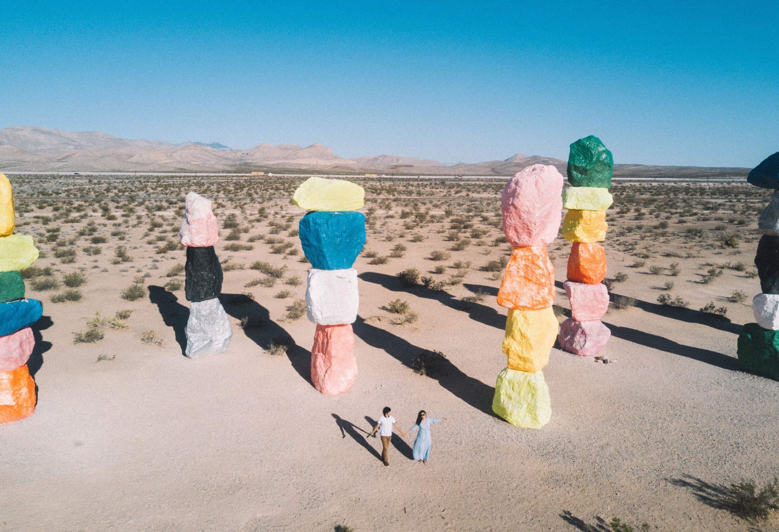 A couple walking among the stacks of painted boulders in Seven Magic Mountains.