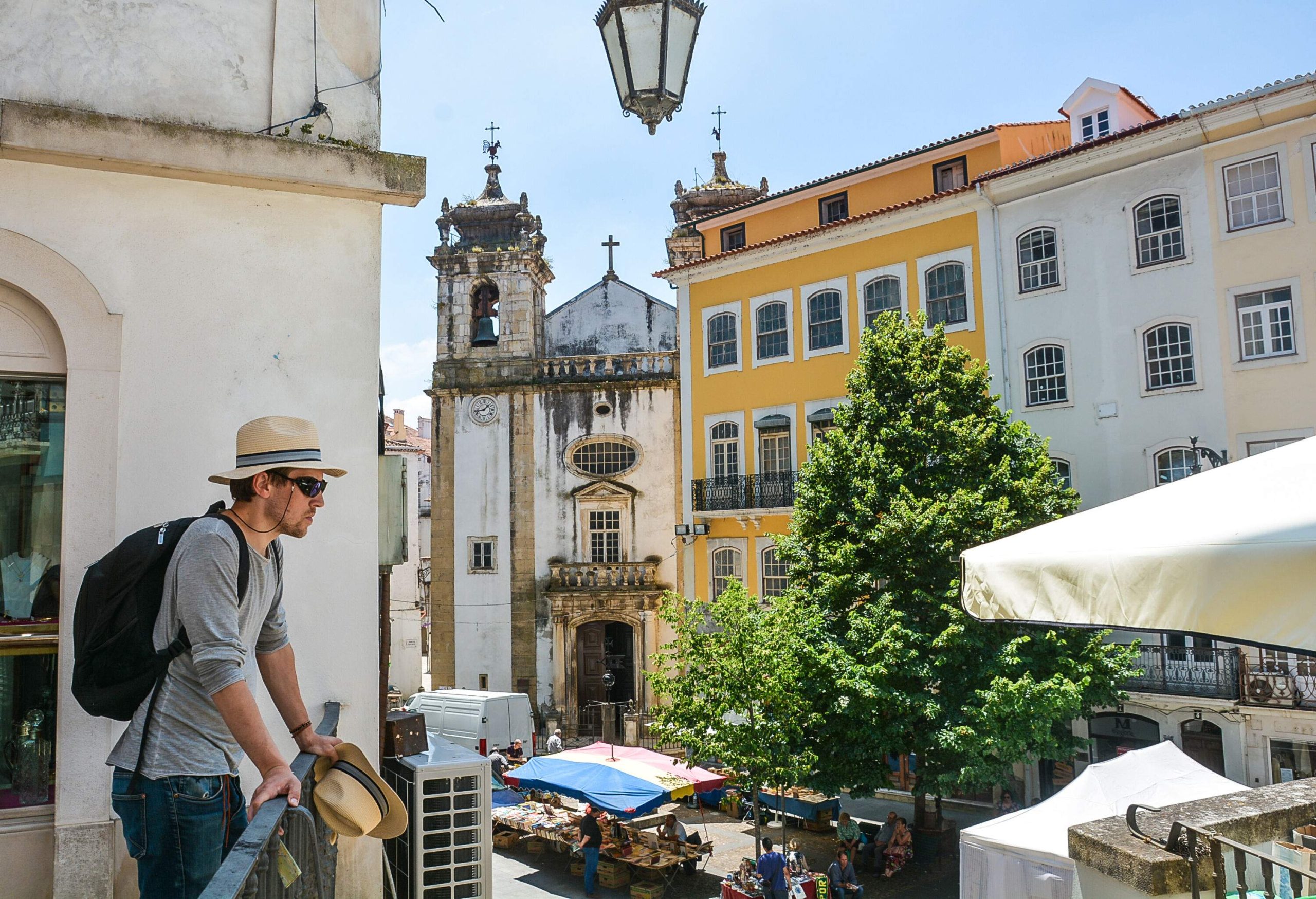 A male tourist standing on a terrace overlooking a street market and colourful buildings.