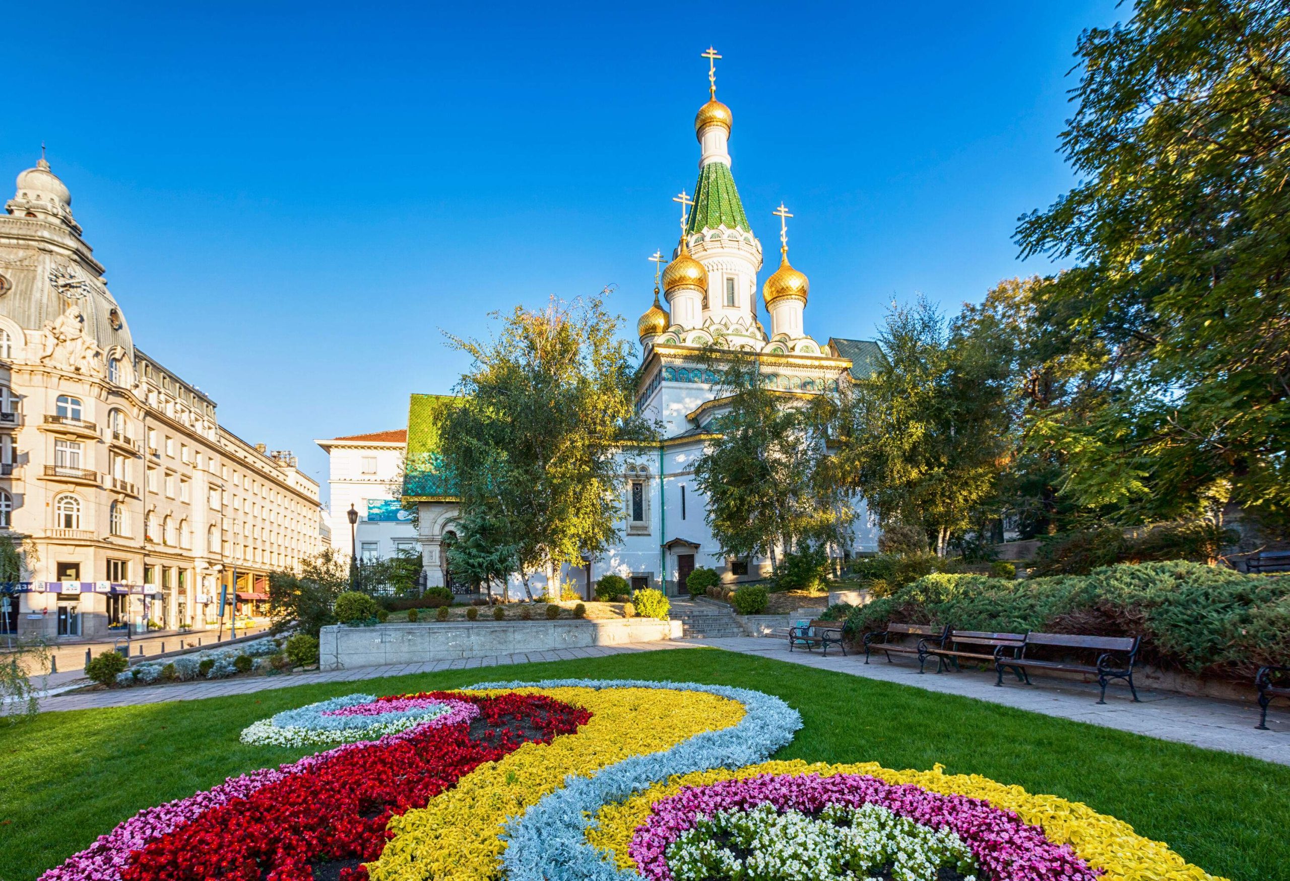 A beautiful landscape of colourful flowers in a park in front of a Russian Orthodox church.