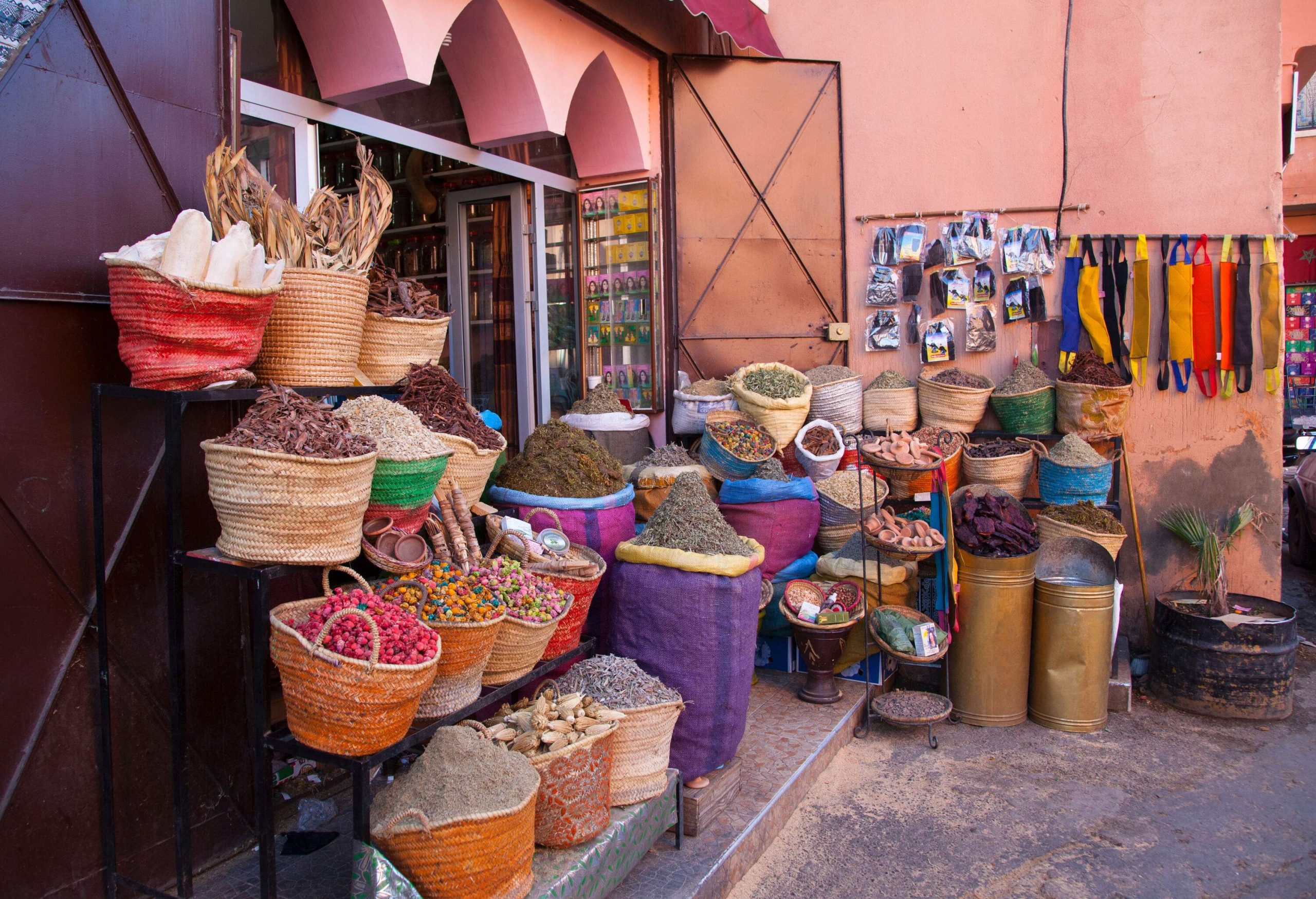 A store with an outdoor display of herbs and spices in straw baskets and woven sacks.