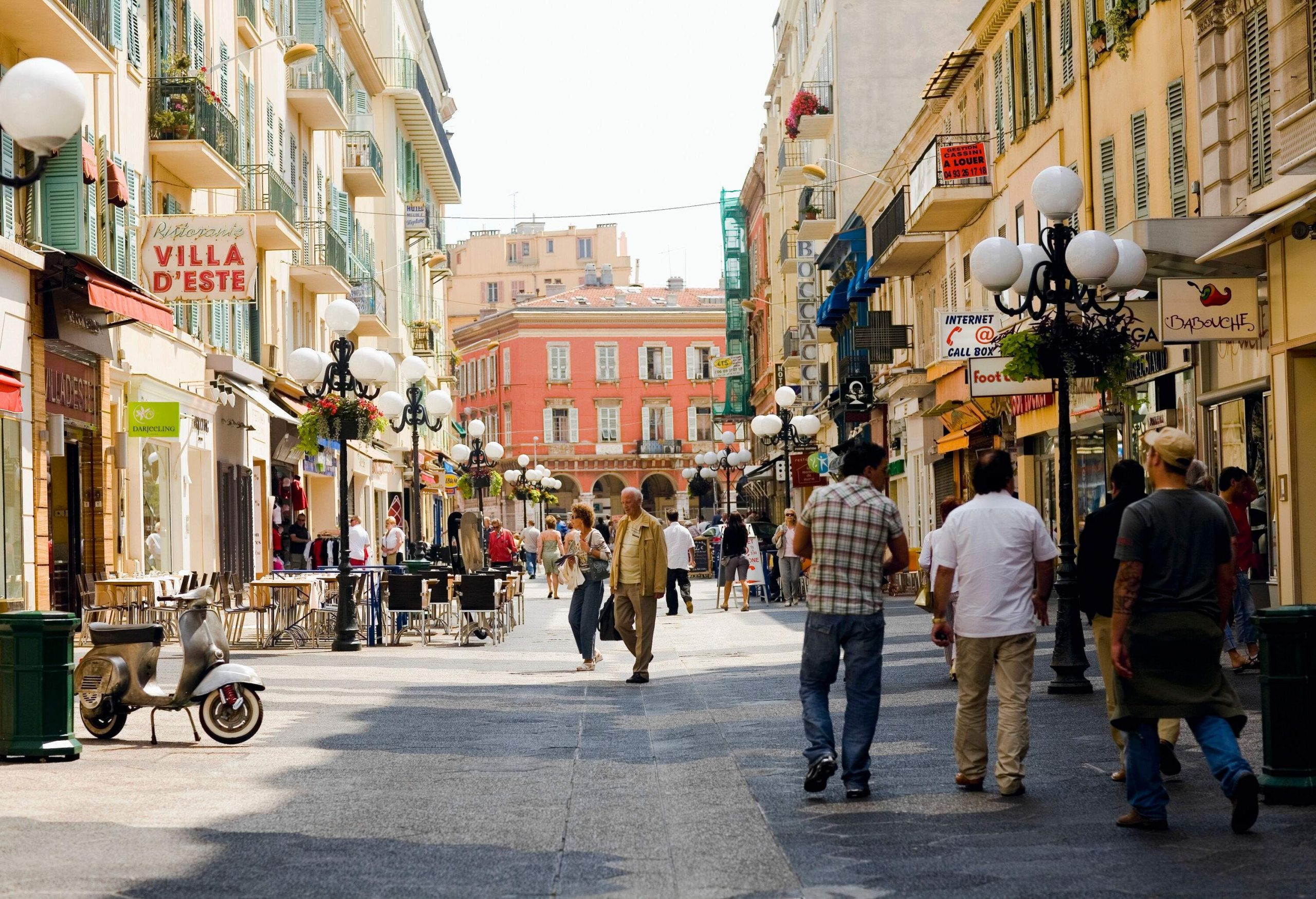 People stroll on a market street lined with colourful classic buildings.