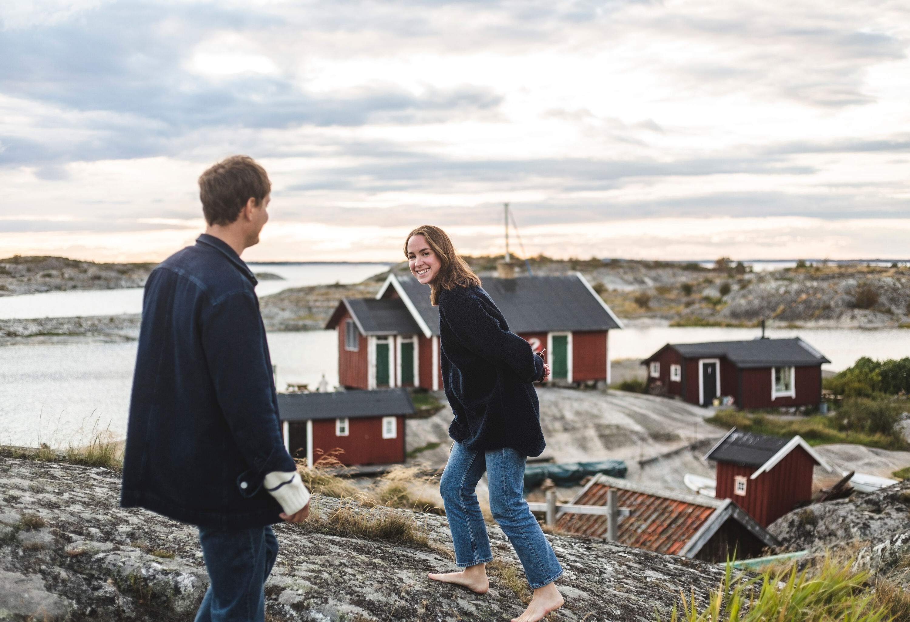 A happy couple on a cliff overlooking the traditional houses by the lake against the cloudy sky.