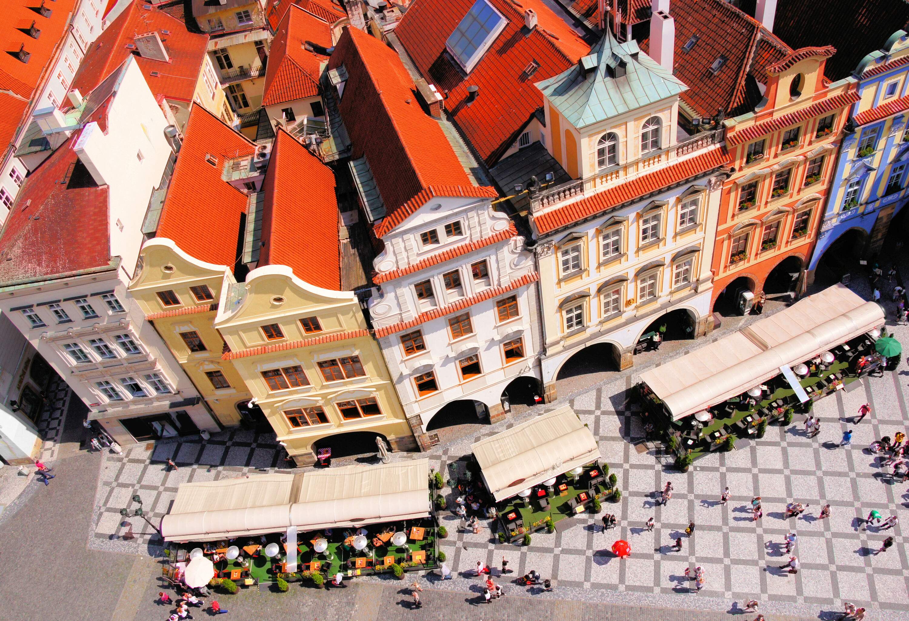 A captivating aerial top view of a crowd in an old town square encircled by stunning classic buildings featuring red brick roofs.