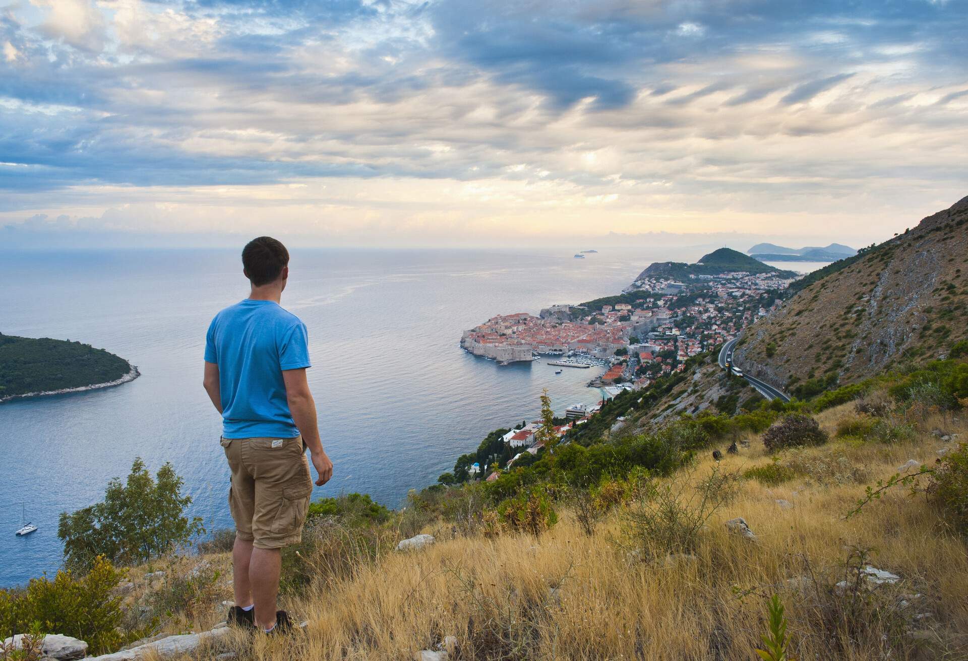 Male hiker standing on a hill looking out to Dubrovnik Old City, Croatia