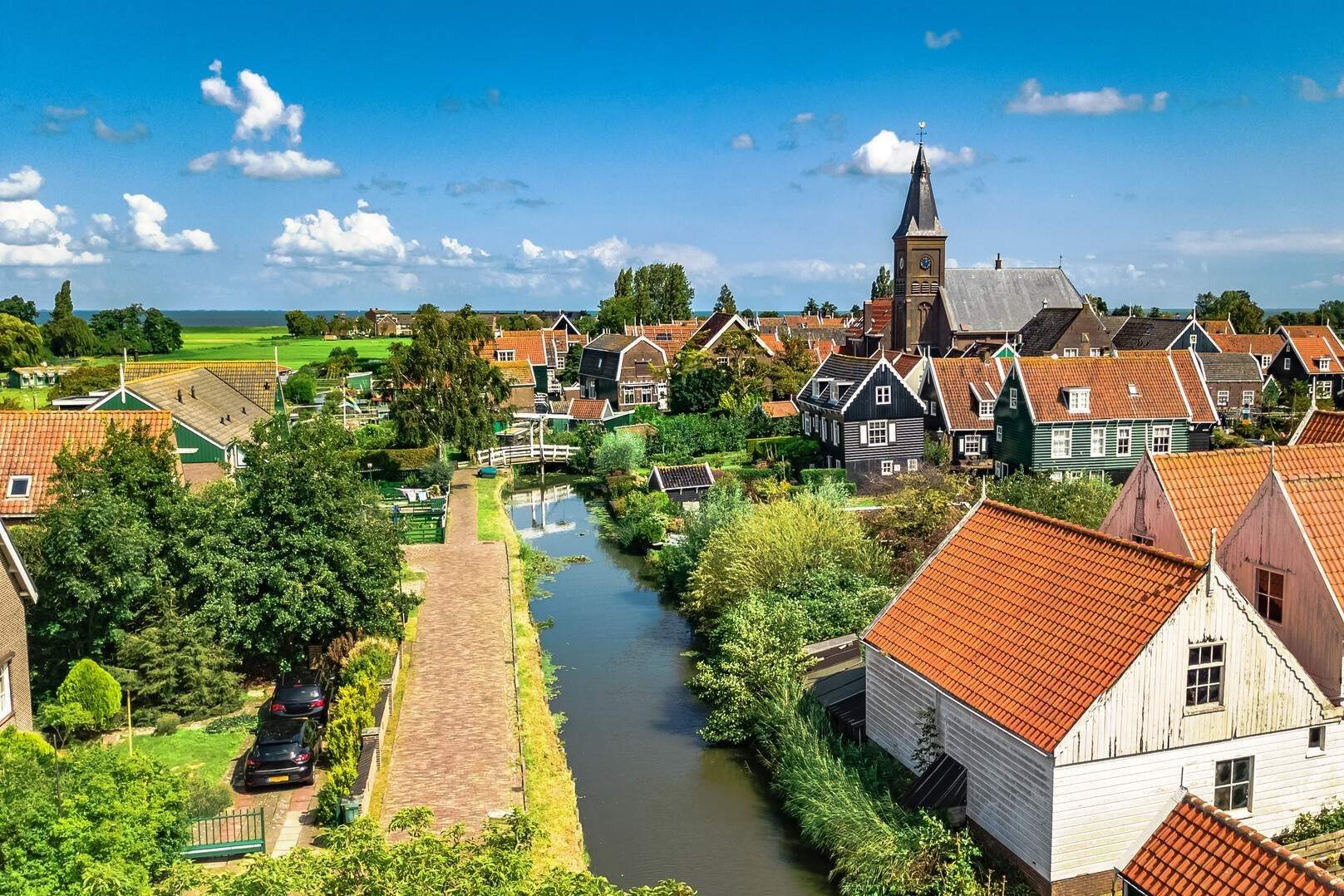 A water canal across a cluster of residences with red tile roofs in a rural village.
