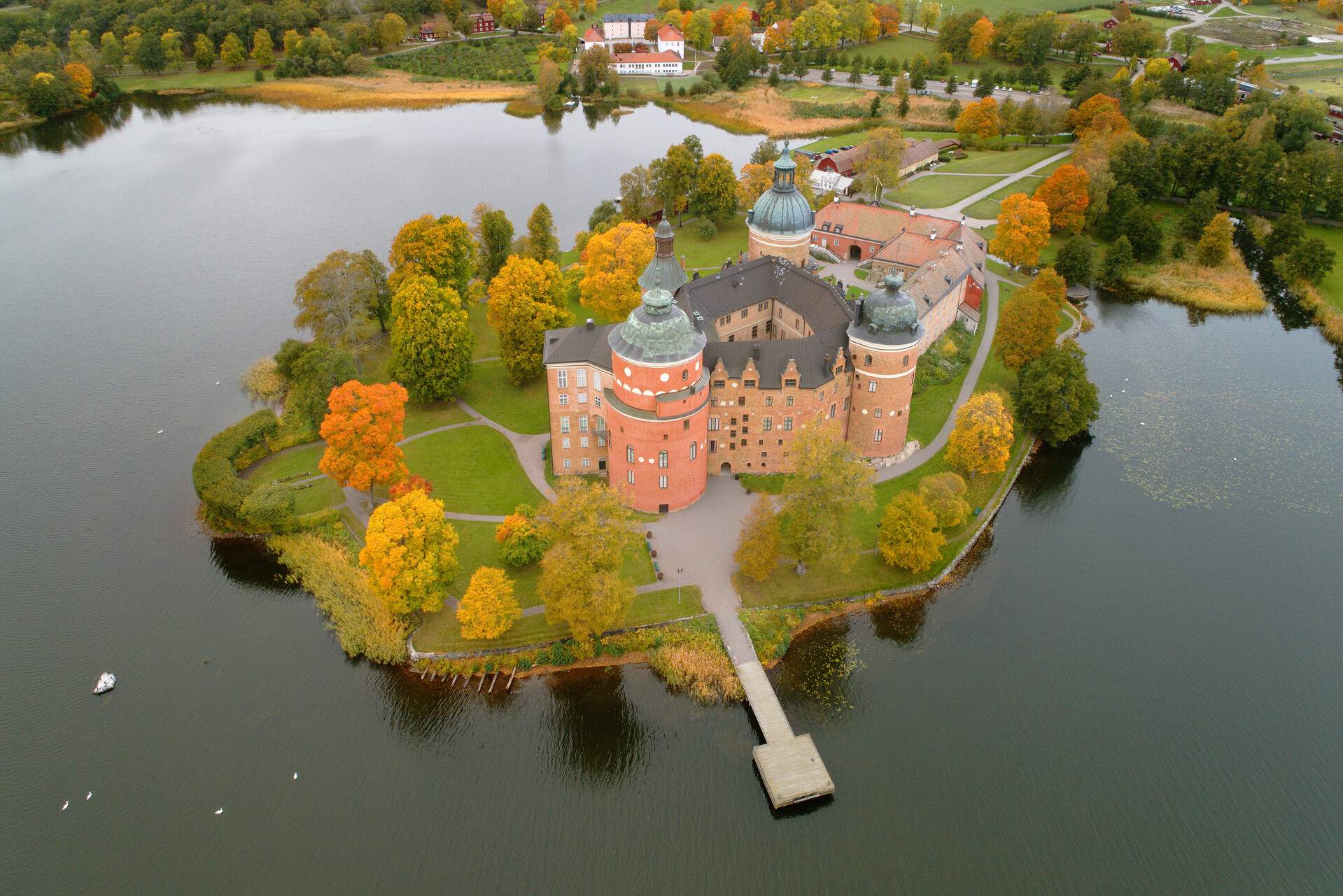 Renaissance castle near a lake, framed by vibrant fall foliage.