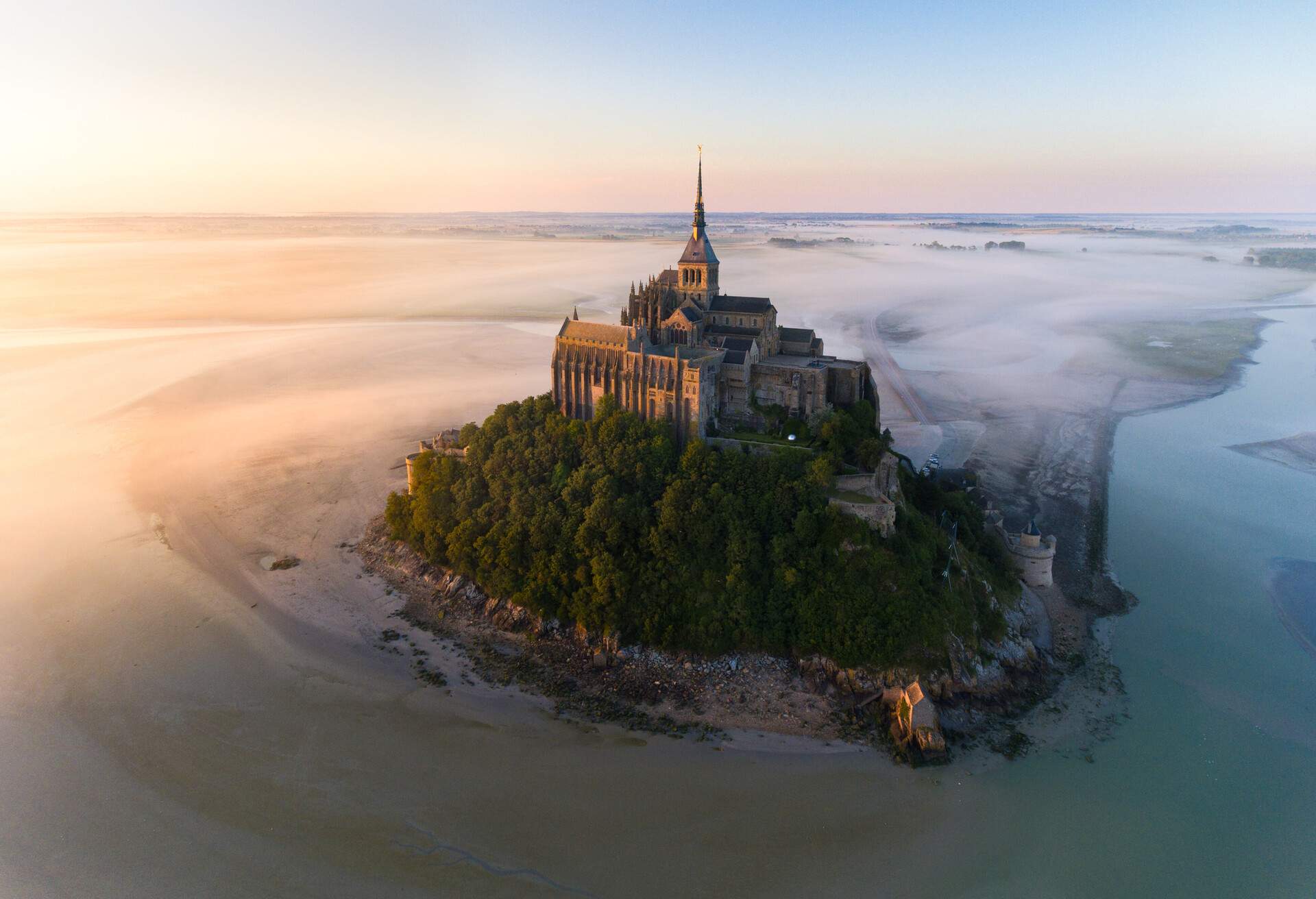 The abbey sat atop Mont Saint-Michel, surrounded by trees and water and shrouded in mist. 