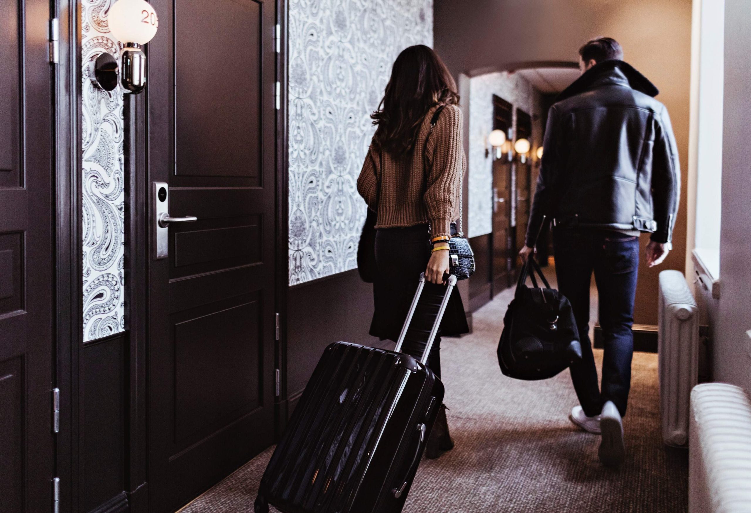 theme_travel_hotel_corridor_rooms_people_couple_walking_luggage_gettyimages-1241453705