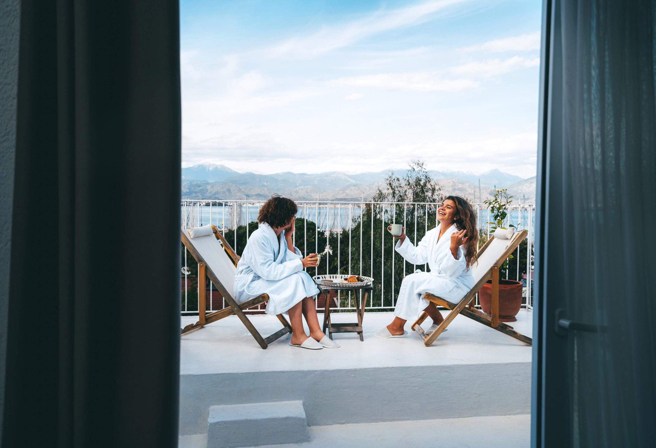 theme_travel_hotel_room_balcony_people_women_friends_bathrobes_gettyimages-1481003466-scaled