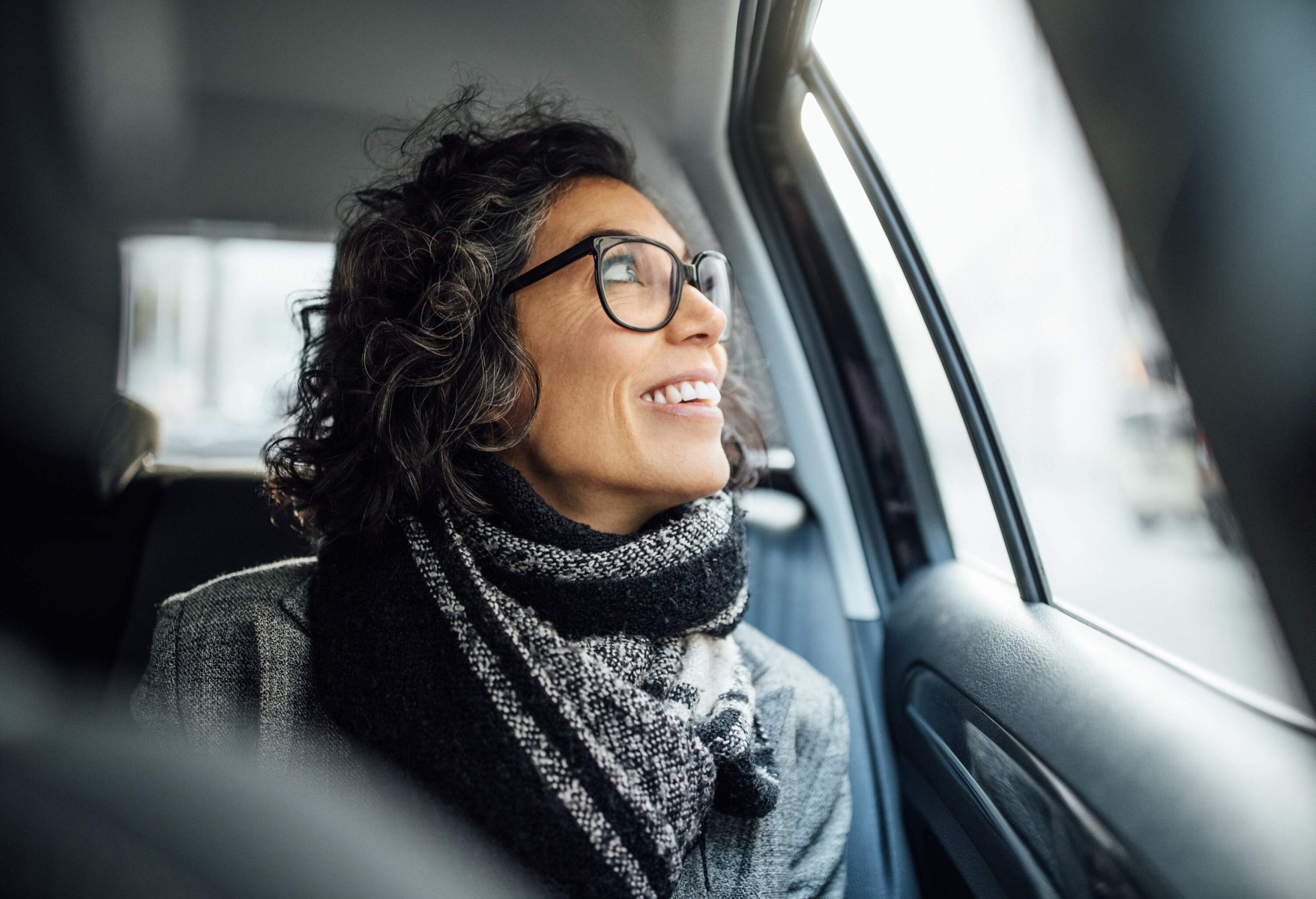 dest_germany_berlin_car_backseat_person_female_smiling_looking_out_window_gettyimages-1129377235