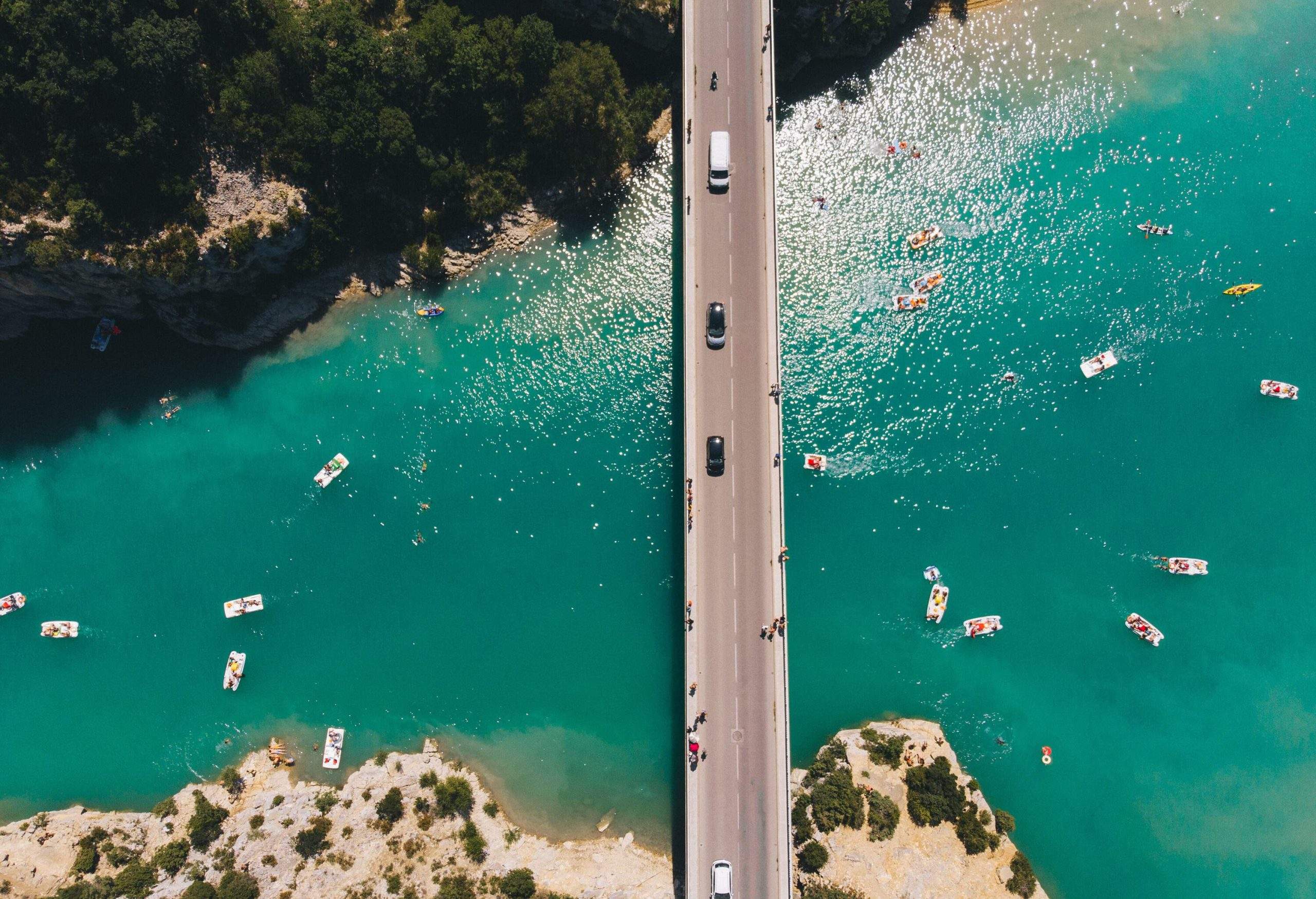 Cars cross a bridge over a lake that is crowded with boats.