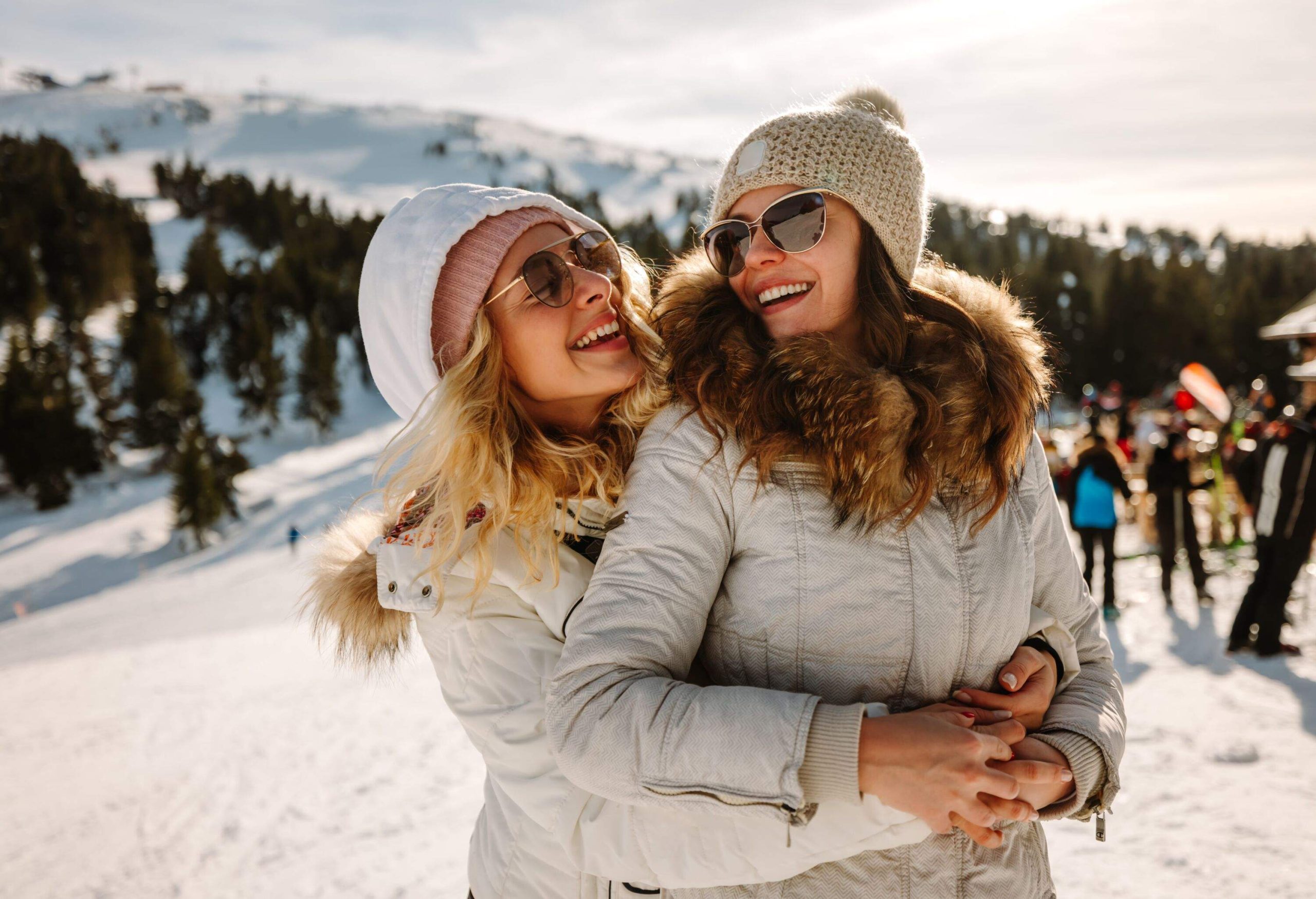 Portrait of happy female couple on winter vacation, standing and hugging on mountain