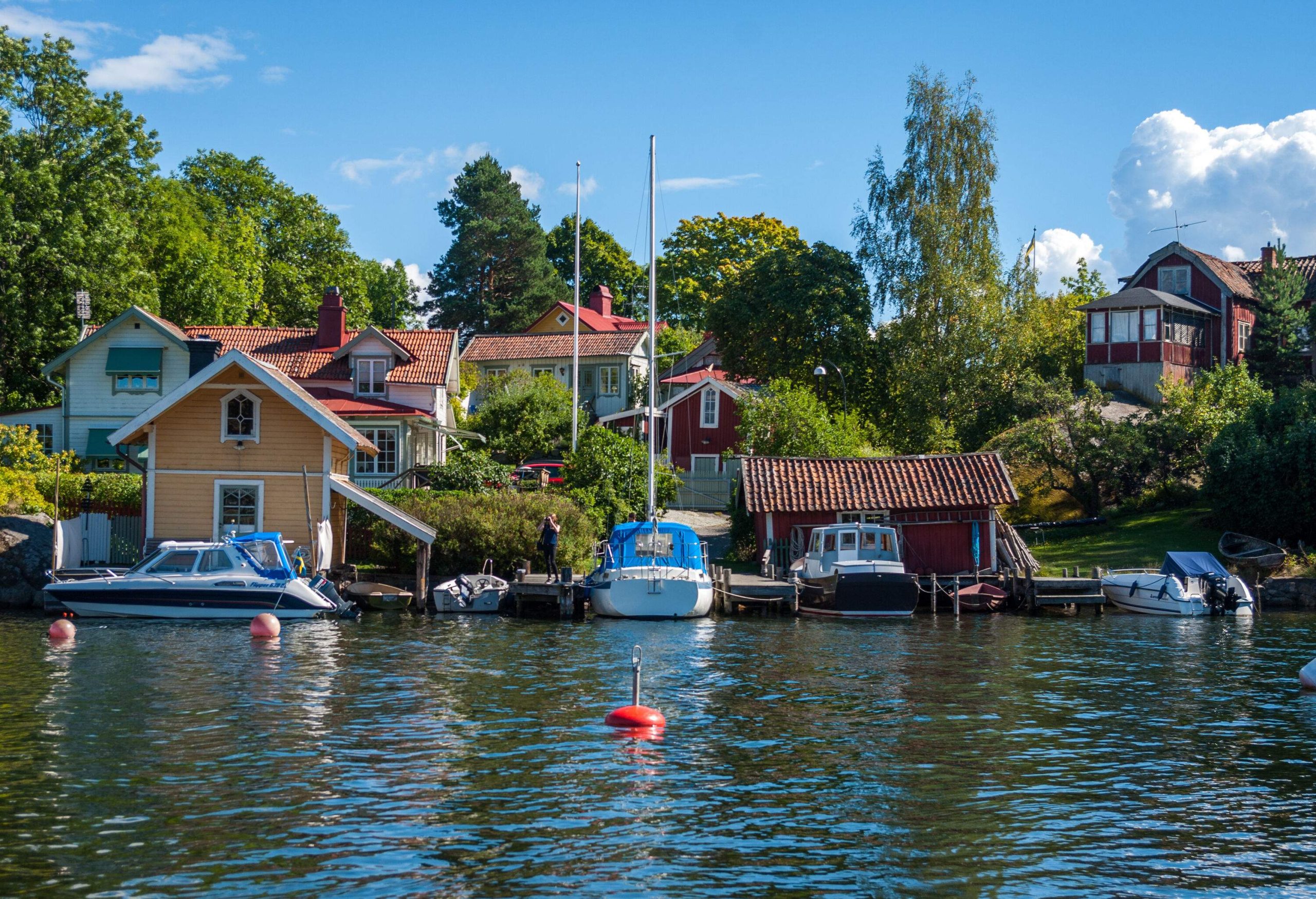 A row of boats docked on the harbour beside the waterfront houses.