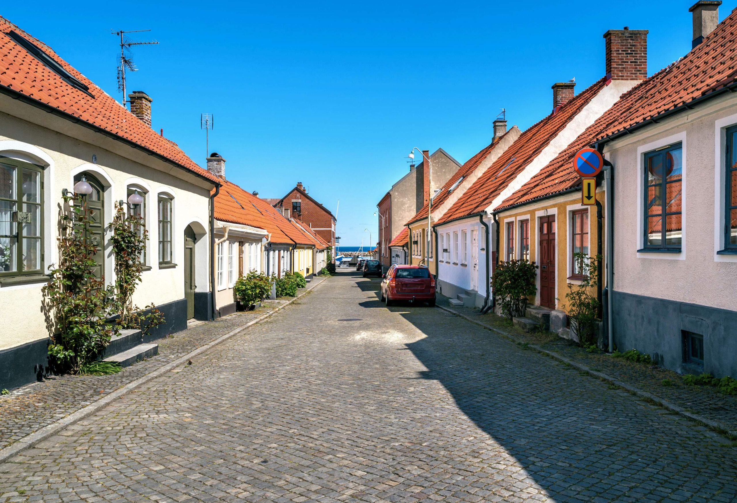 A cobbled street lined with traditional and colourful houses with red brick roofs.