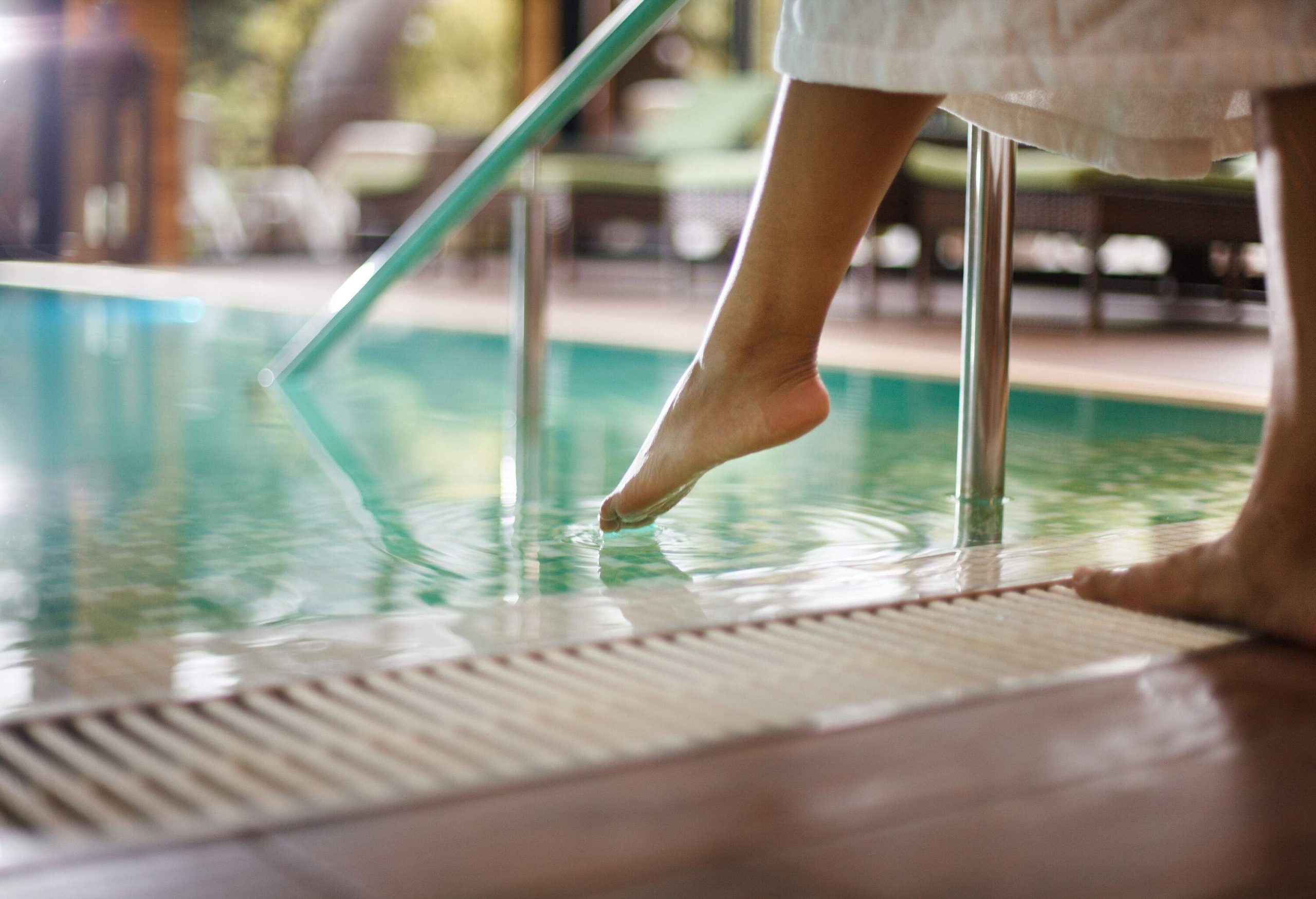 A person dips its toe into a swimming pool.