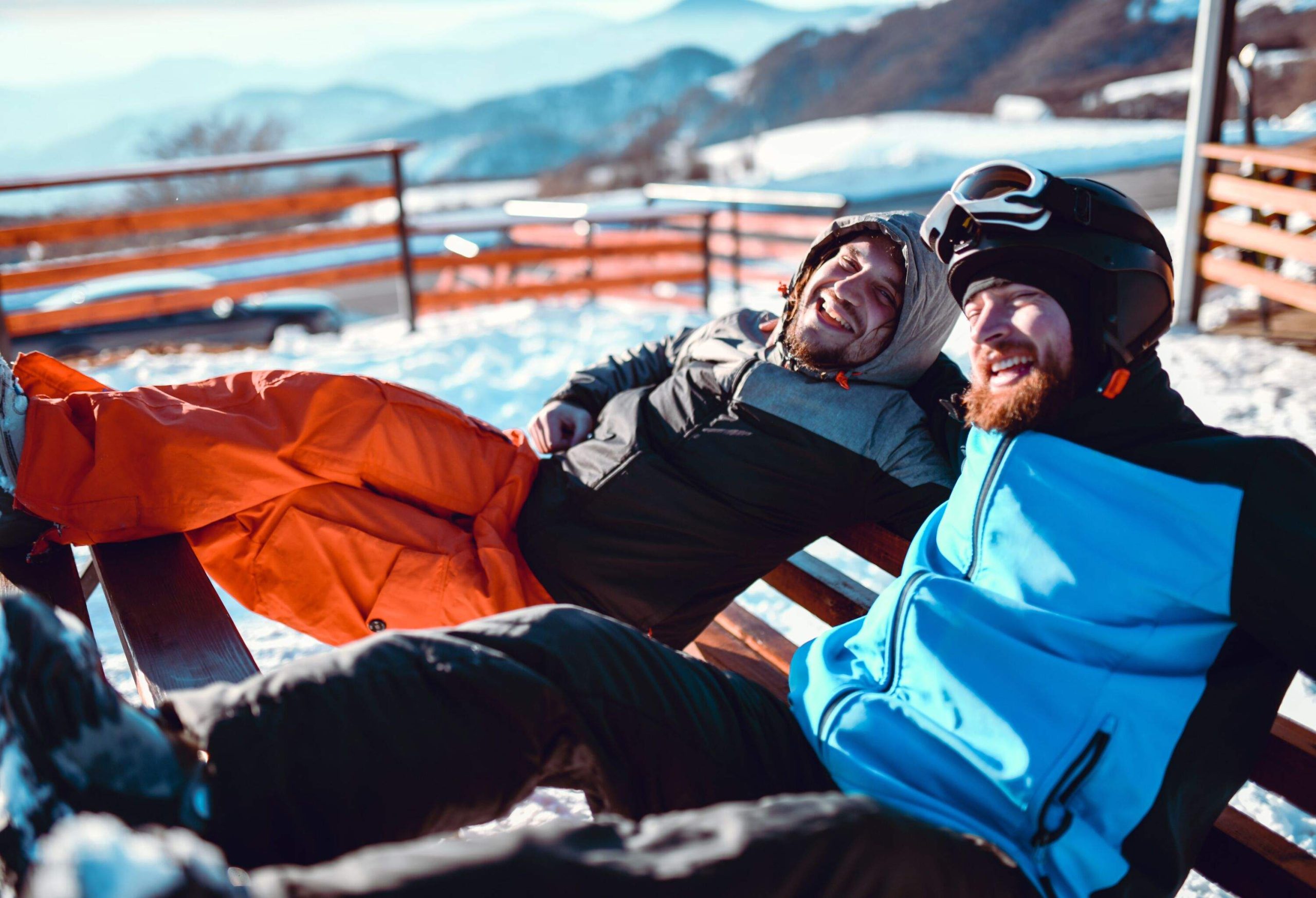 Gay Couple Embracing After Skiing On Mountain