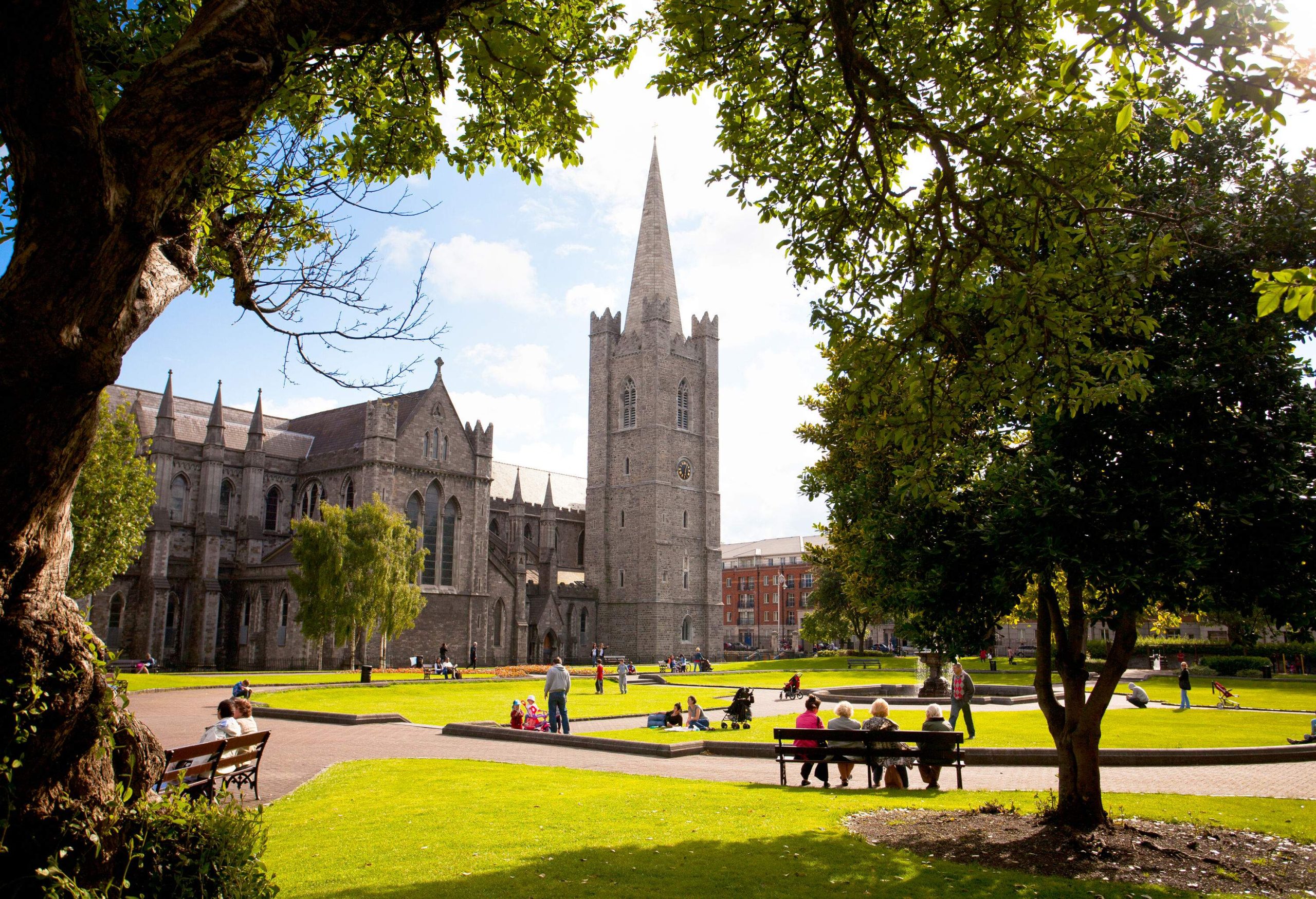 People enjoying a pleasant day at a park in front of St Patrick's Cathedral.