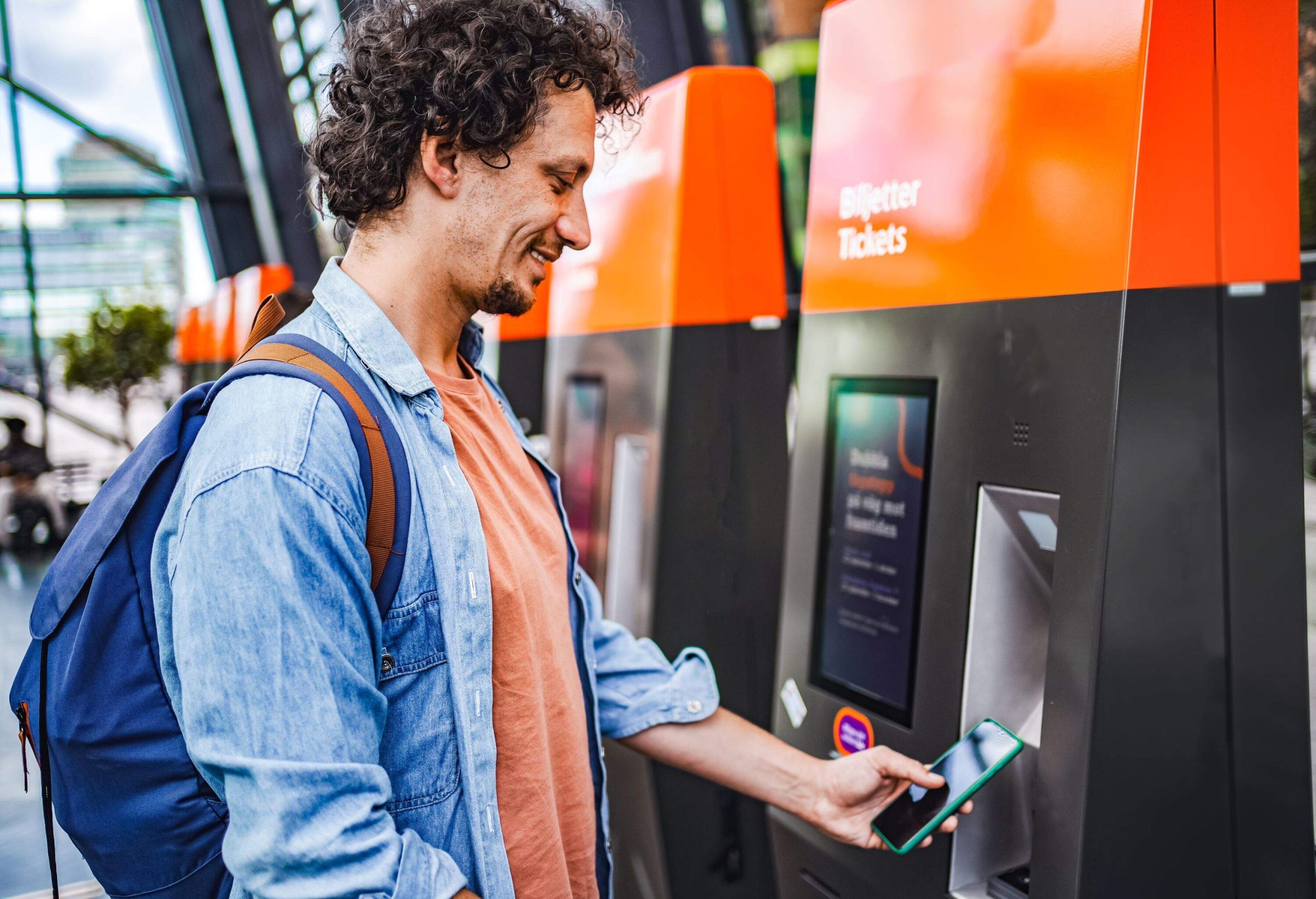 Male passenger buying a ticket on a self-service ticket machine at the station