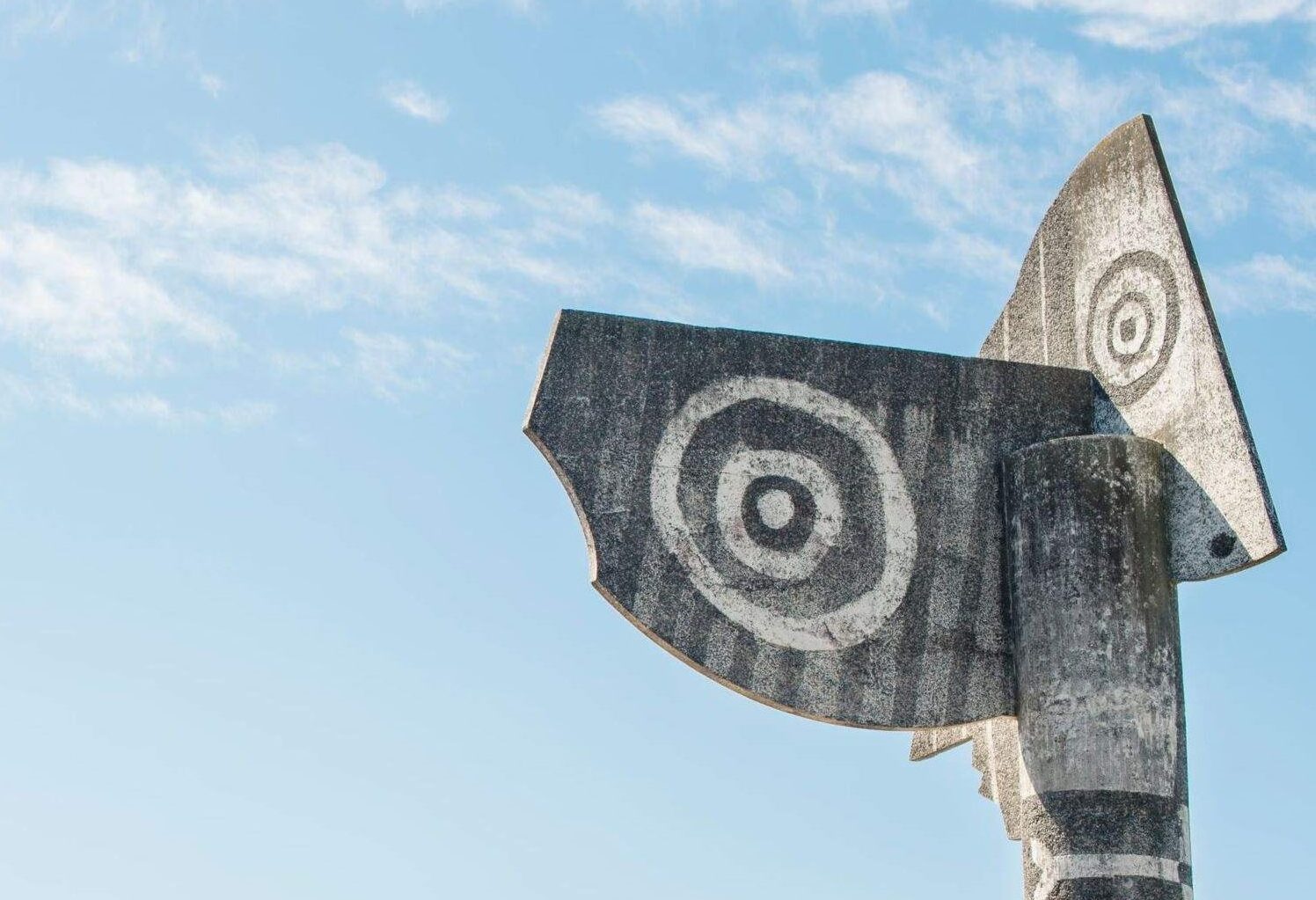 tall concrete sculpture by a lake