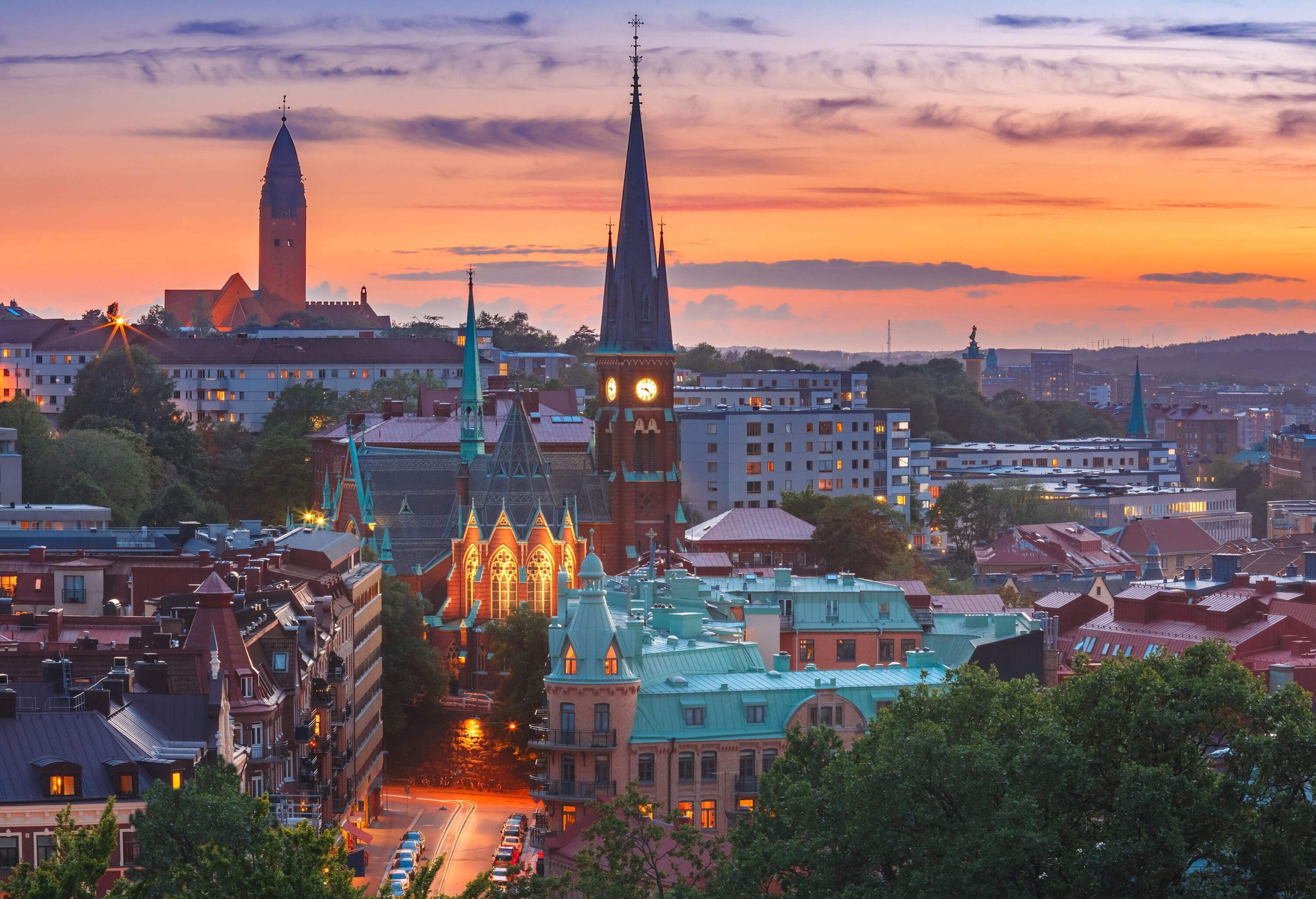 Under the waning light of sunset, a clock tower stands out among the cityscape.