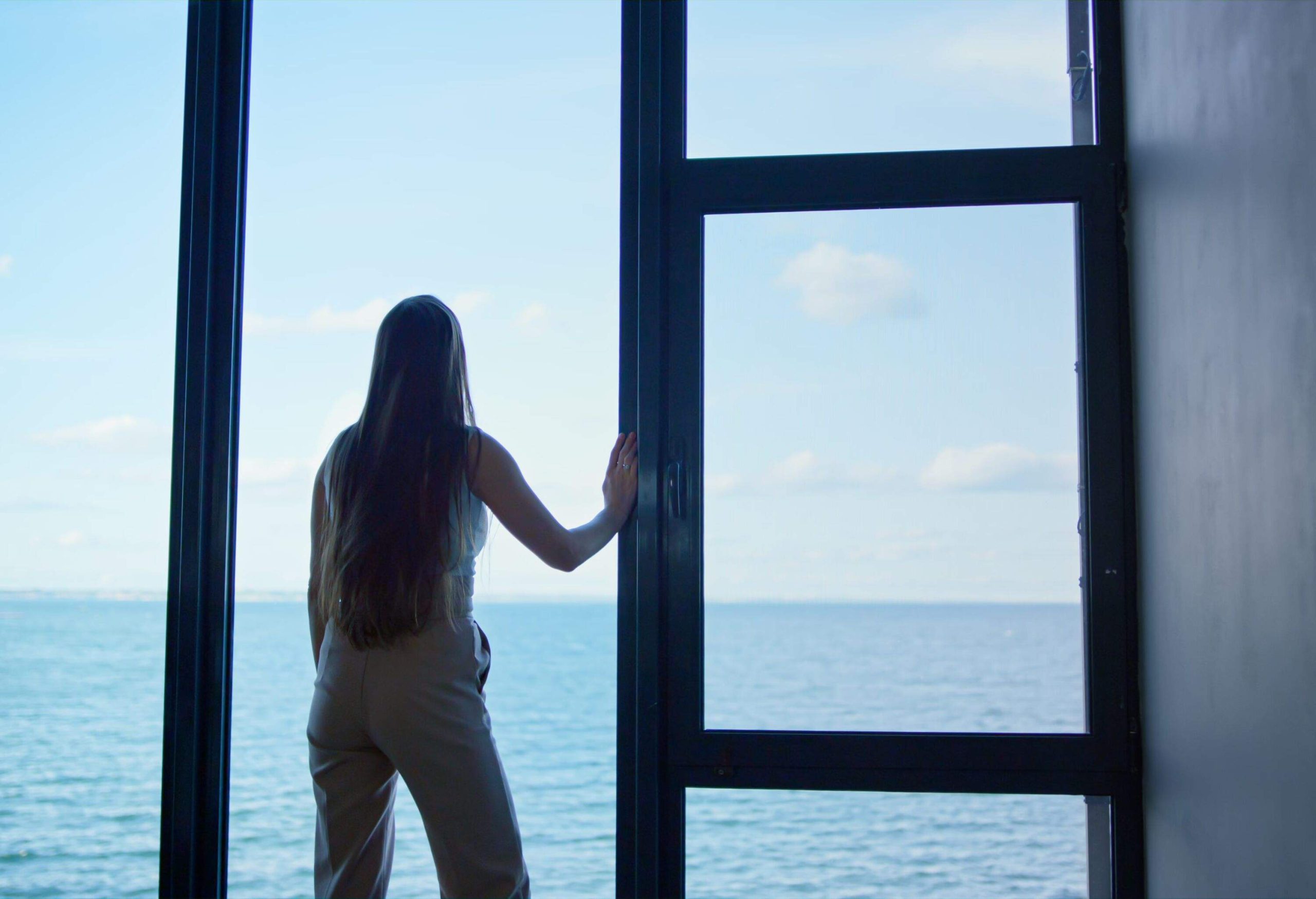Lonely woman thinking problems at panorama window. Upset businesswoman crying making decision at sea rear view. Depressed ceo financial manager silhouette rest in office. Emotional breakdown concept