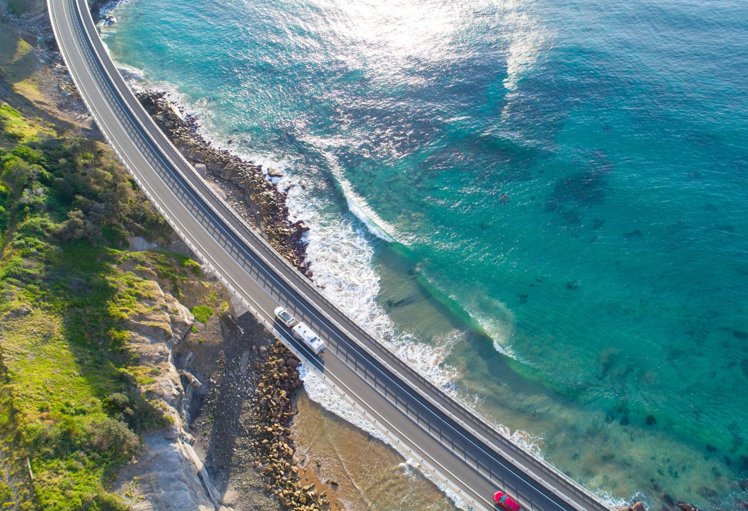 The Sea Cliff Bridge spans across the ocean, with cars traversing the scenic route, offering a breathtaking and exhilarating experience of man-made infrastructure amidst the stunning natural environment.
