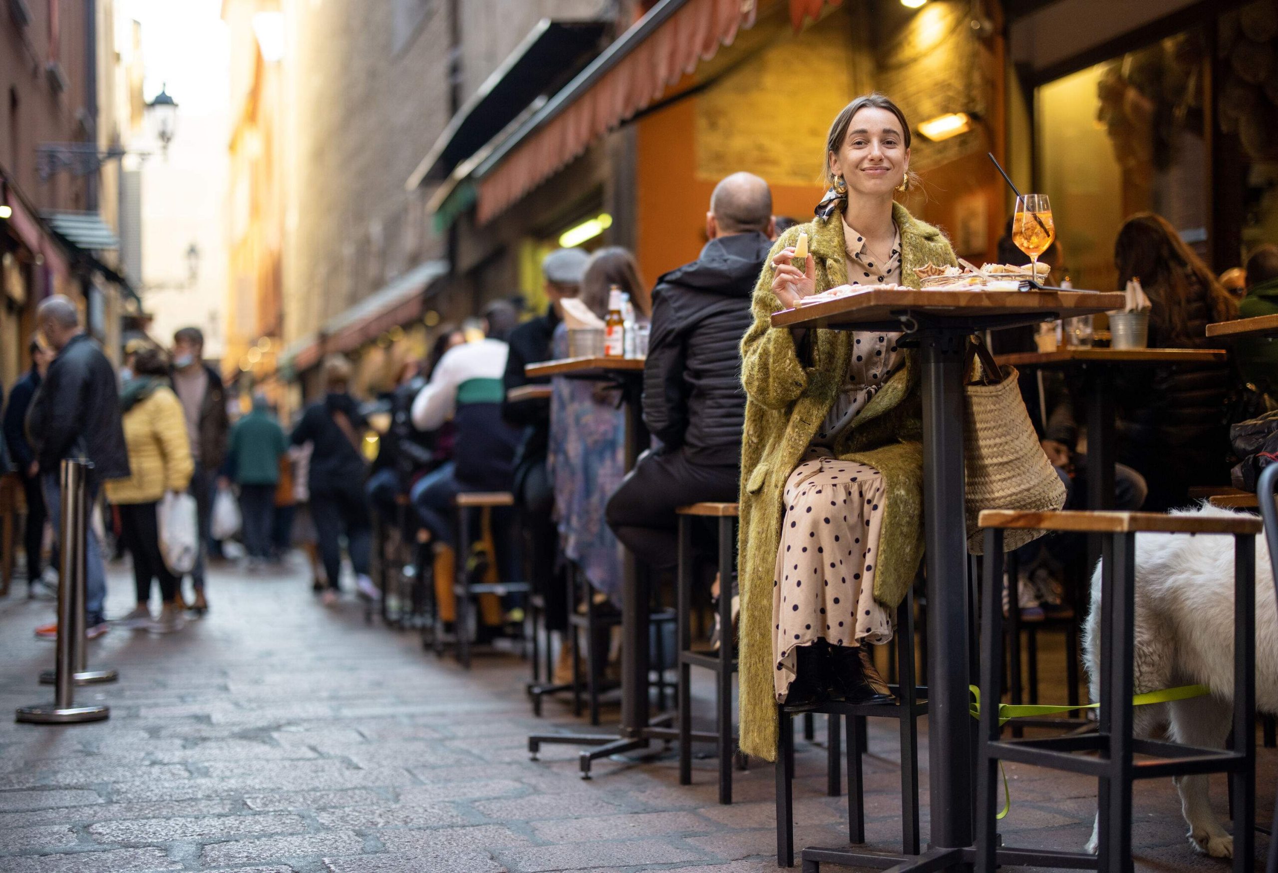 A woman with other customers prefers al fresco dining on the cobbled street.