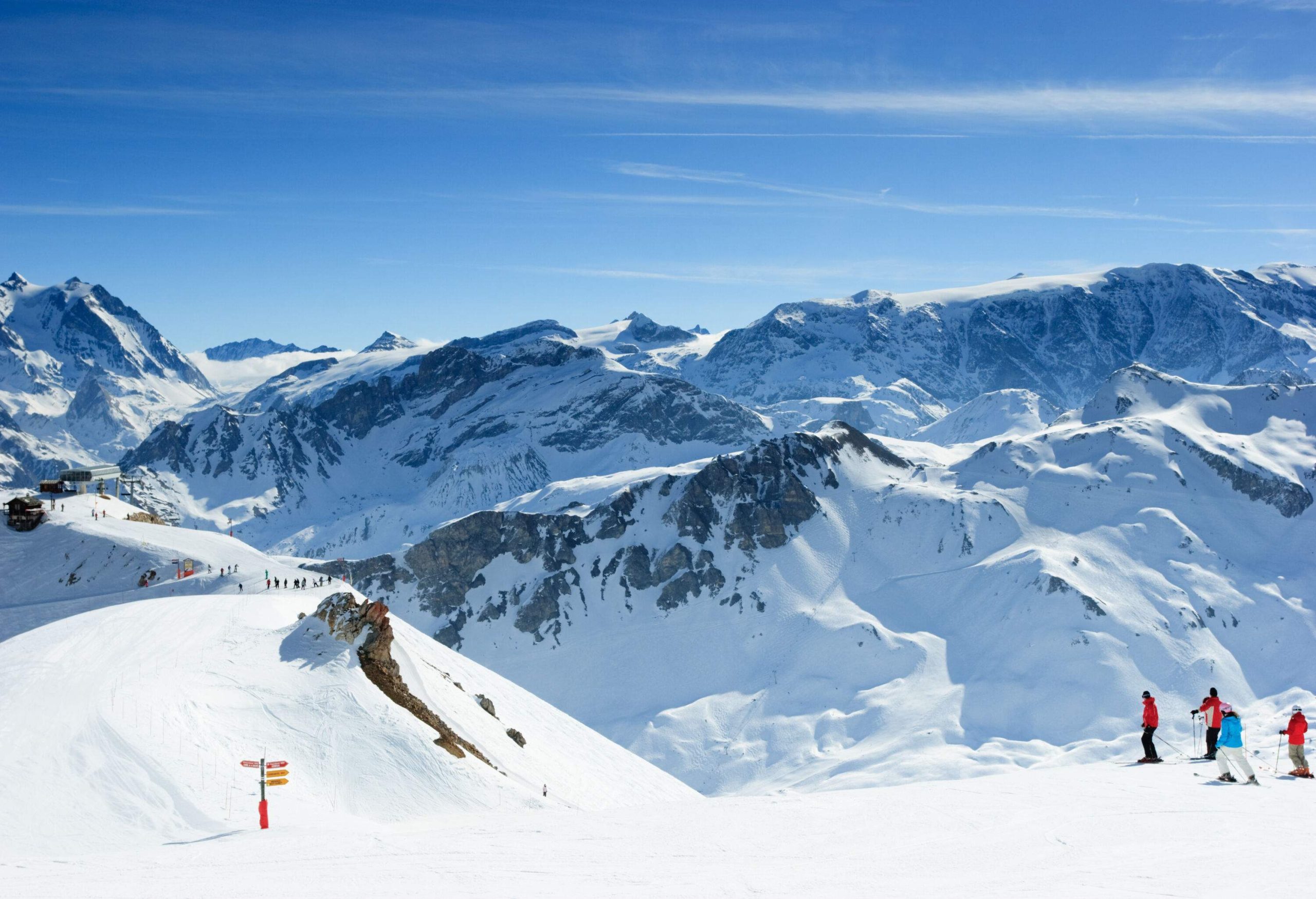 A mountain range blanketed with snow and populated with skiers.