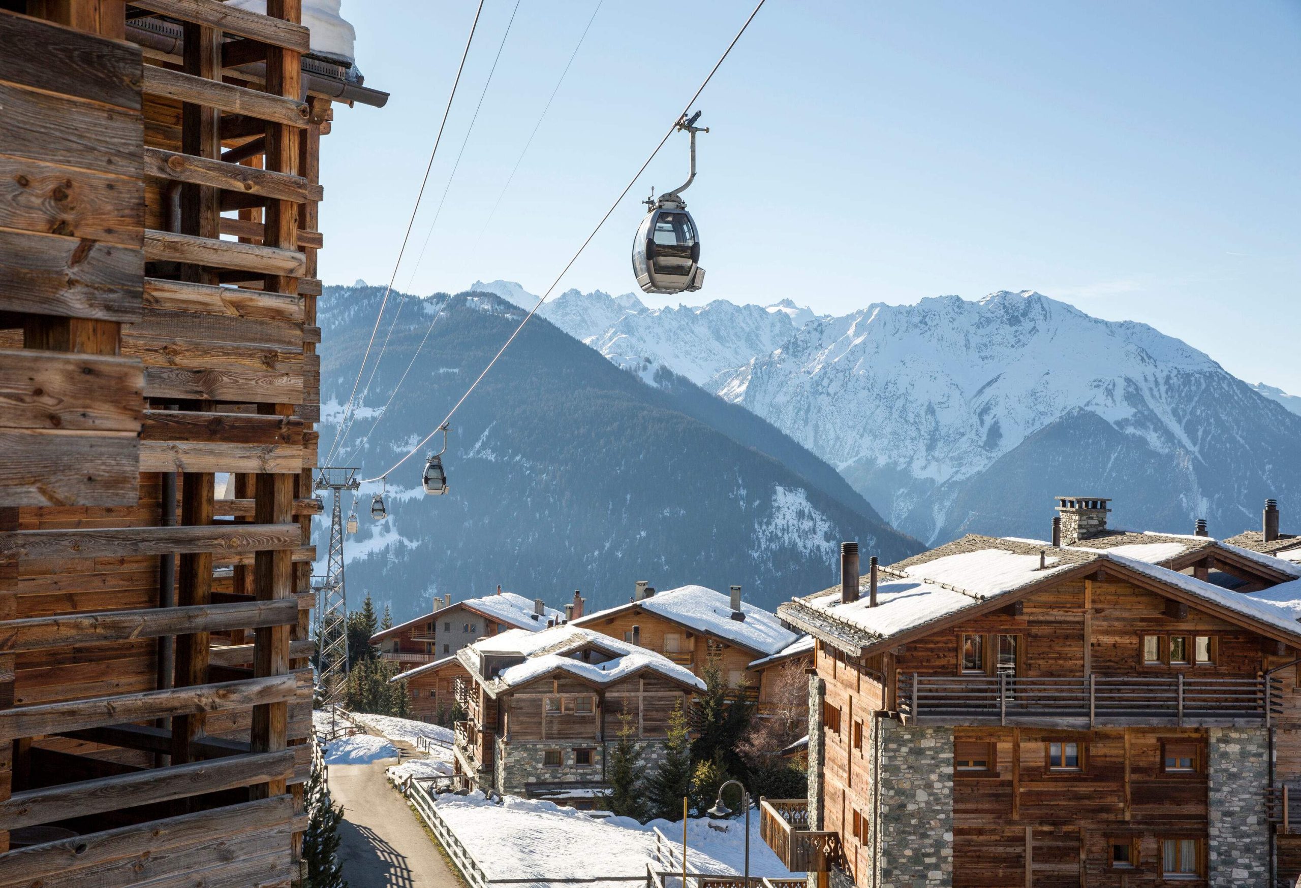 Several cable cars travel back and forth above the roofs of wooden houses.