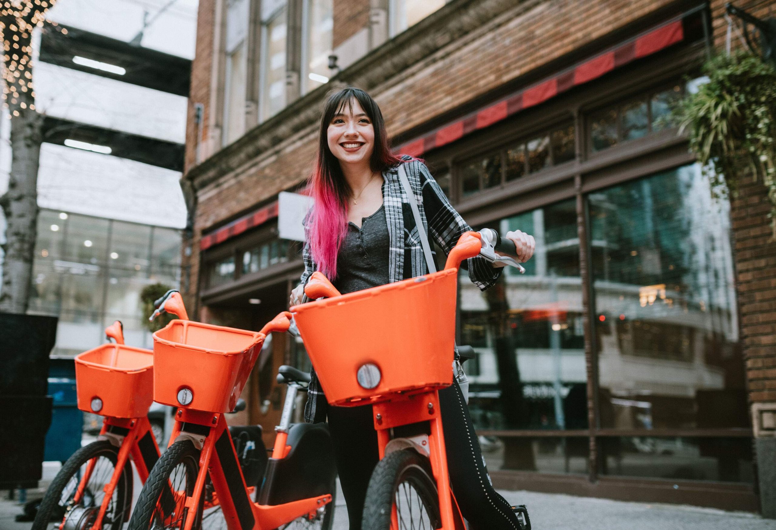 A young lady tourist rides an orange bicycle to go around the city.