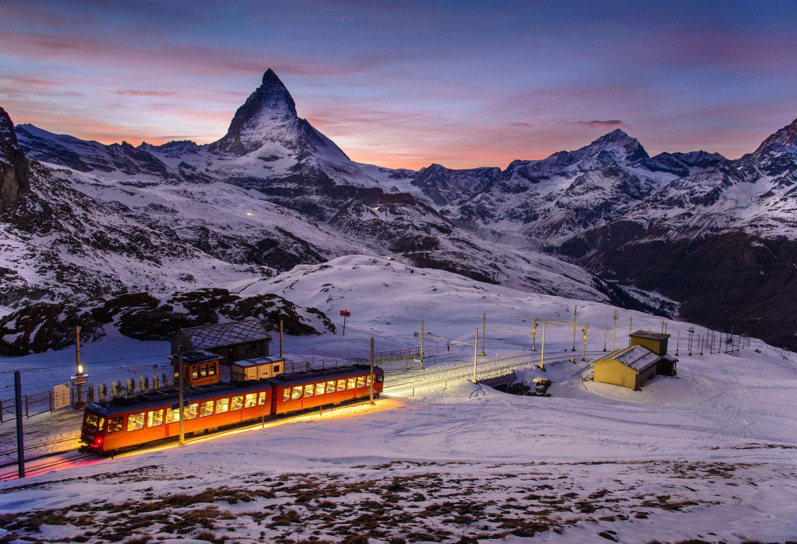 The mountain rack railway has a train confidently navigating the challenging terrain, ascending amidst the rugged, rocky slopes.