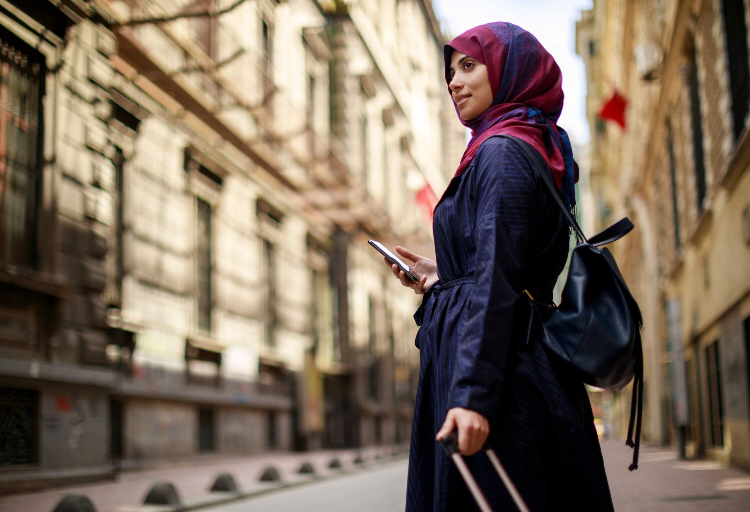 A woman pulling a suitcase as she walks through a city street.