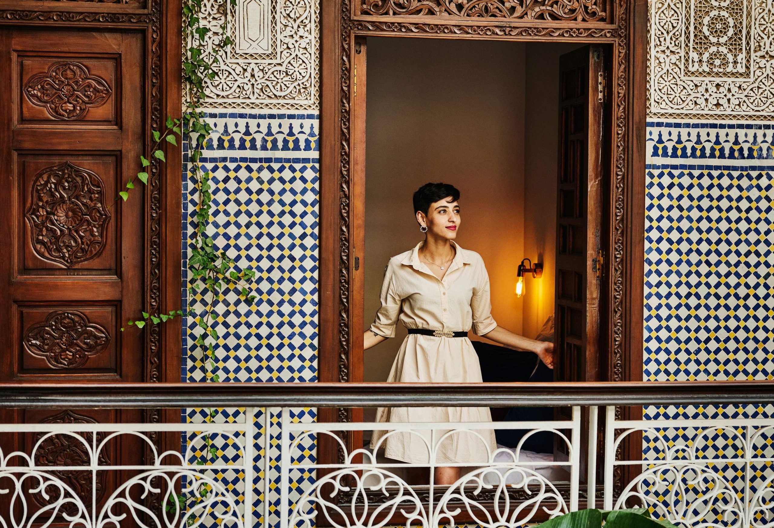 Wide shot portrait of smiling woman standing in window of bedroom in raid while on vacation in Marrakech